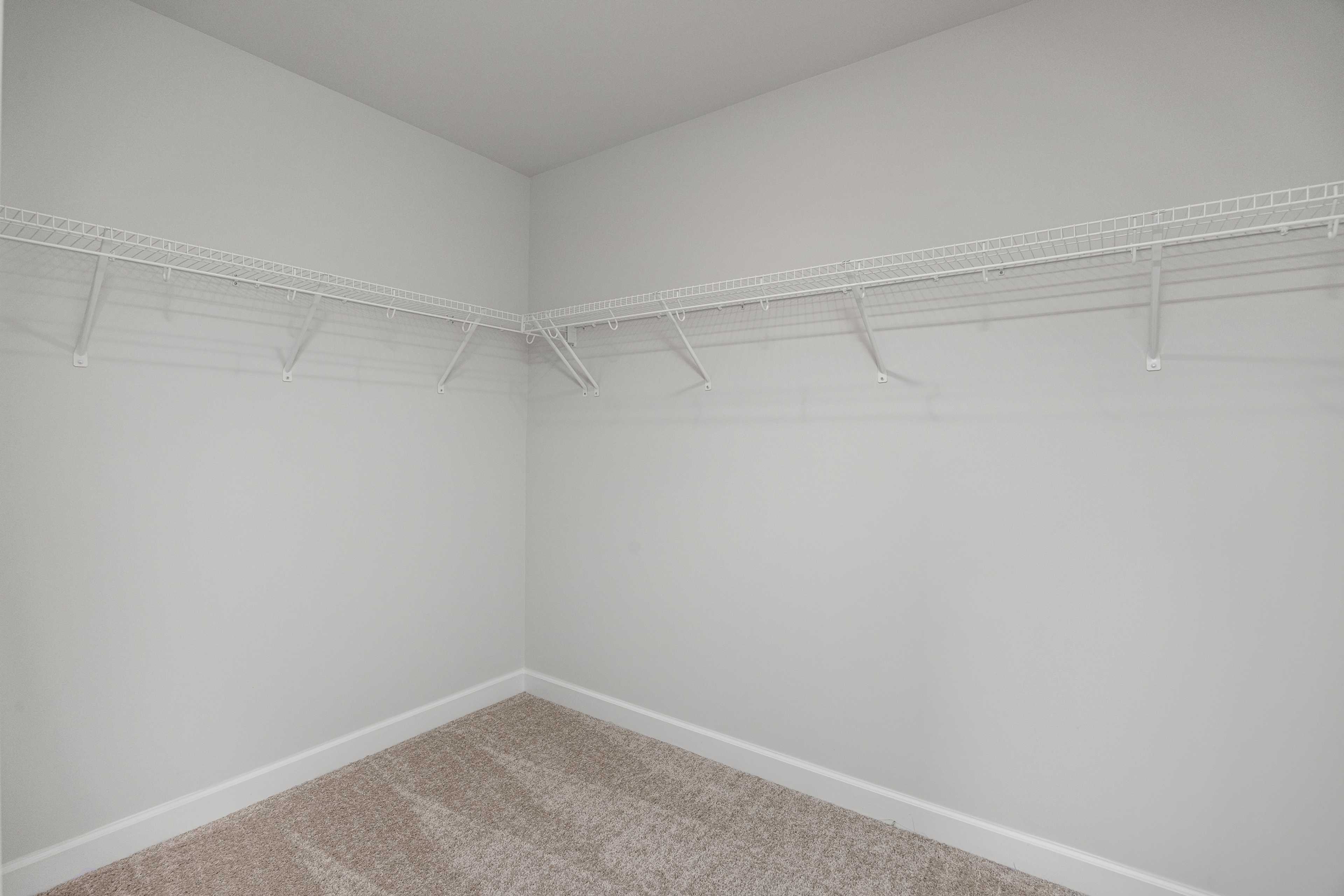 Spacious walk-in closet in Springvale home, Fuquay-Varina NC with white walls, wire shelving and beige carpet floor