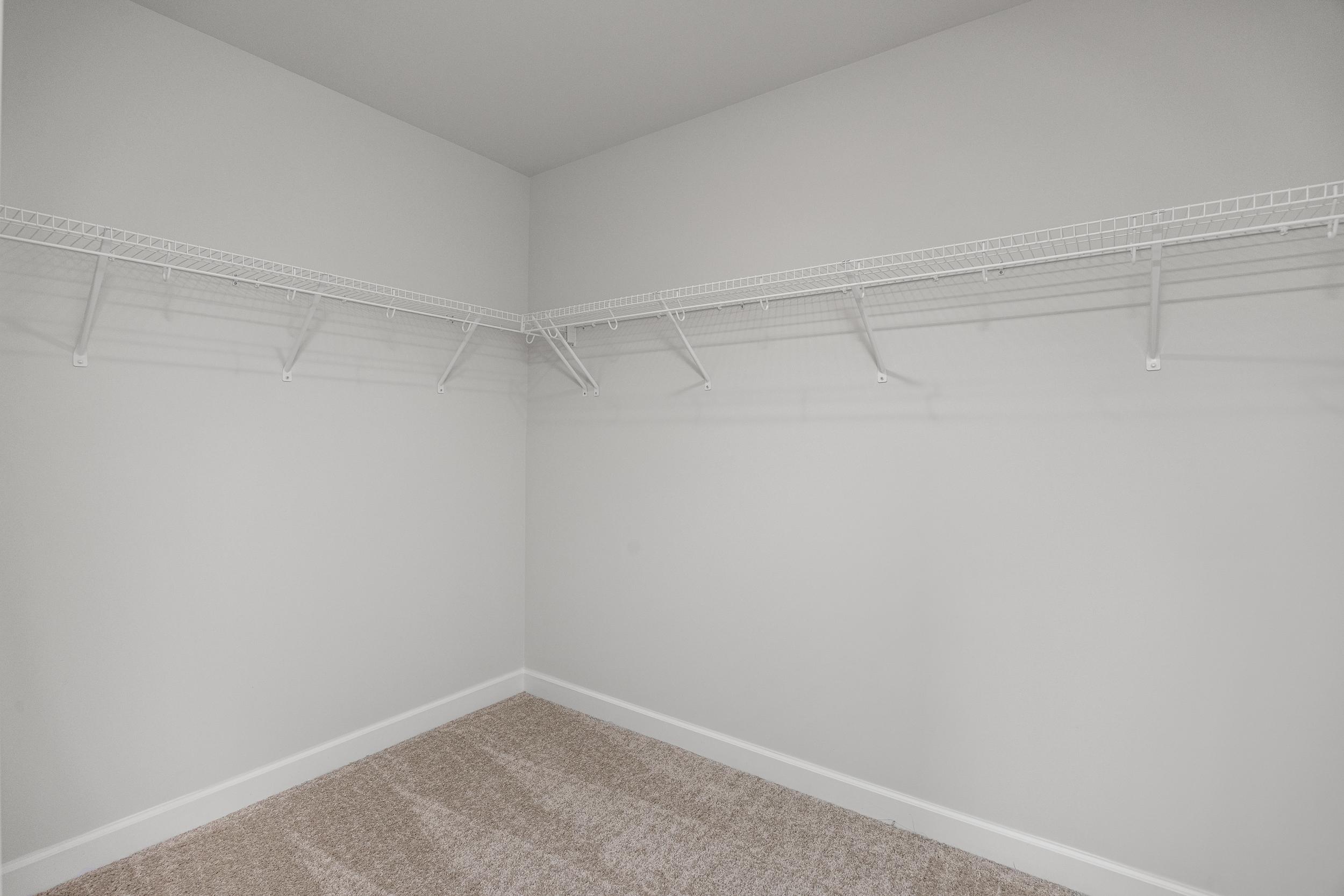 Spacious walk-in closet in Springvale home, Fuquay-Varina NC with white walls, wire shelving and beige carpet floor