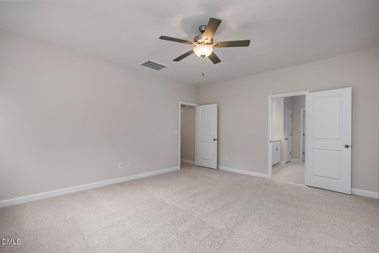 Spacious bedroom with carpet, ceiling fan, and walk-in closet in The Hickory II C floor plan by Davidson Homes in Montrose.