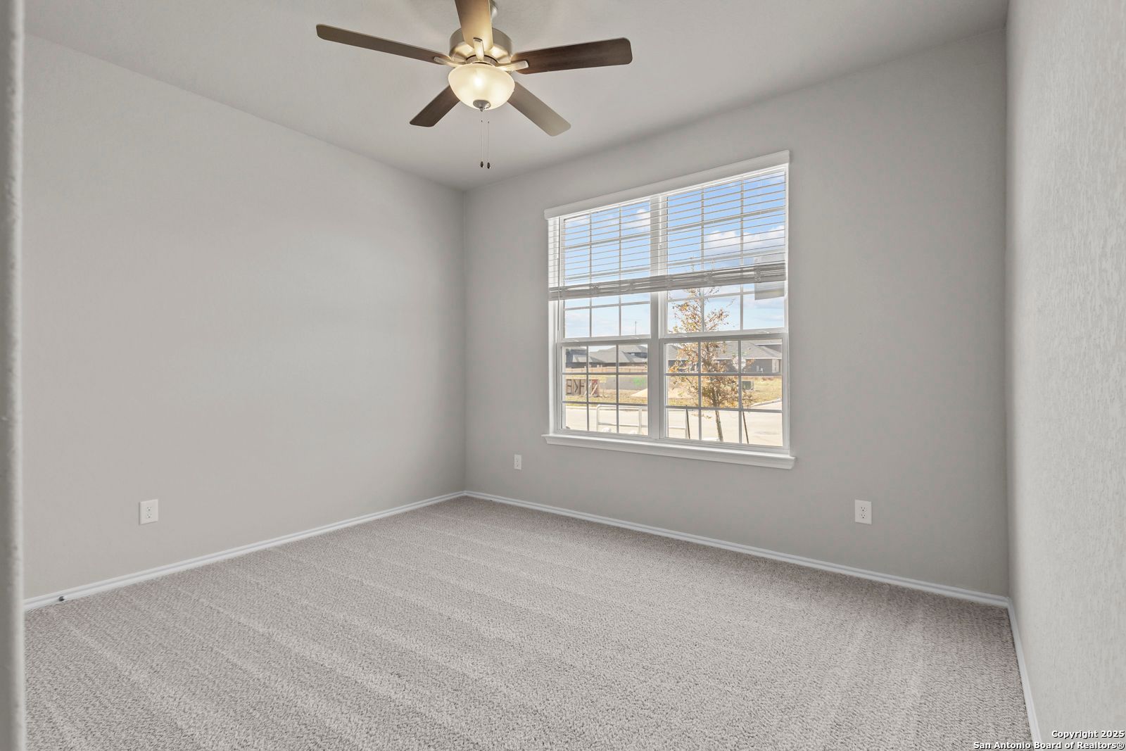 Bright secondary bedroom with ceiling fan, carpet flooring, and large window view in Davidson Homes The Collin B, Seguin, Texas