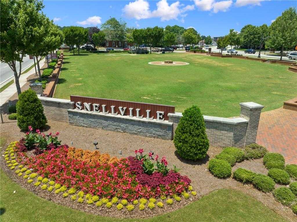 Snellville Georgia welcome sign with vibrant red, yellow, pink flower beds, lush green lawns, brick borders, and tree-lined backdrop