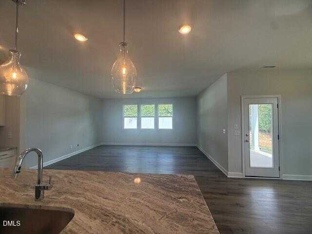 Spacious open-concept great room with kitchen island, pendant lights, large windows, and sliding doors in Davidson Homes Preston C, Lillington, NC