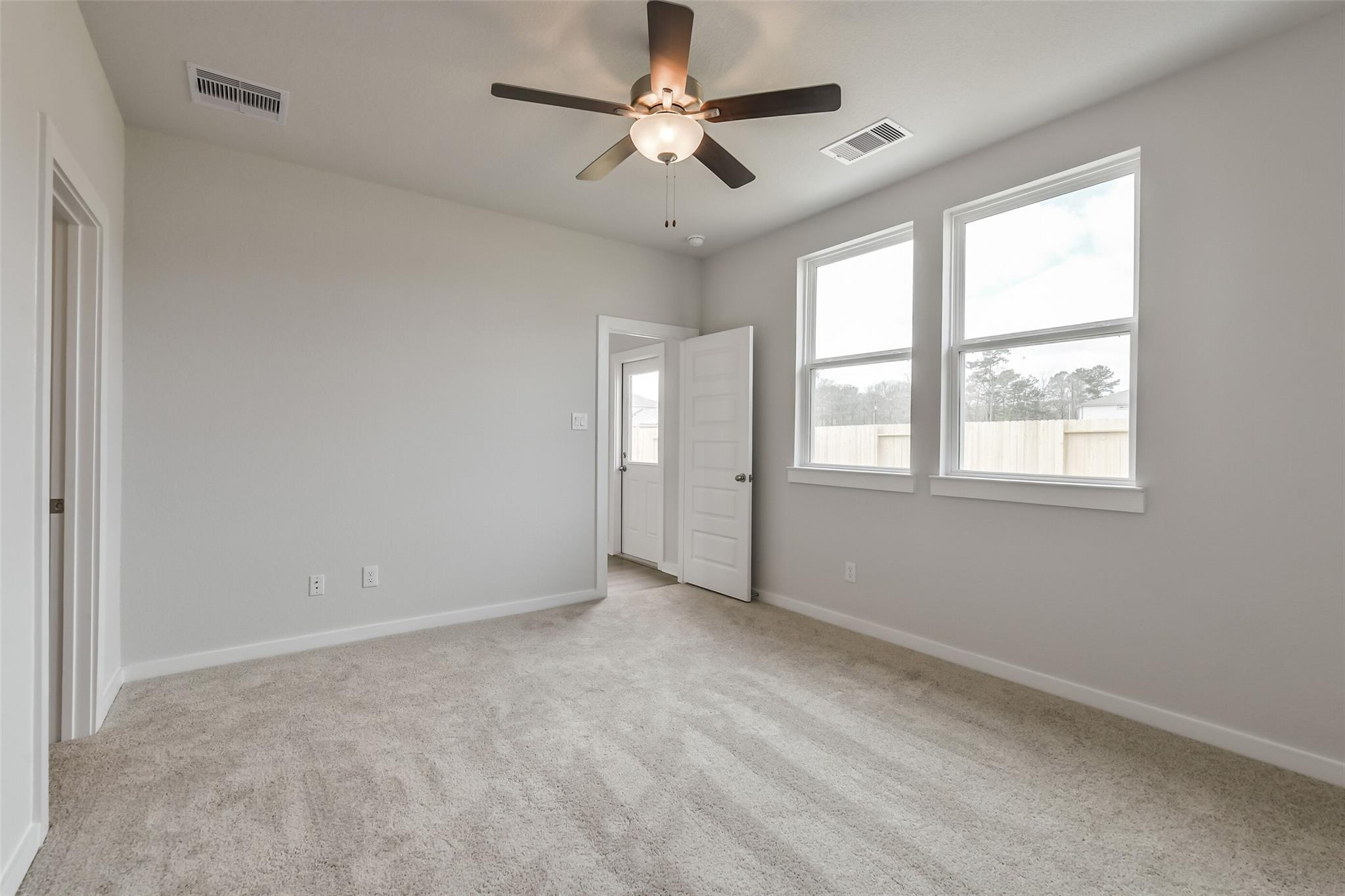 Bright secondary bedroom with ceiling fan, large windows, gray walls, and carpet in Davidson Homes The Frio G, Cleveland TX