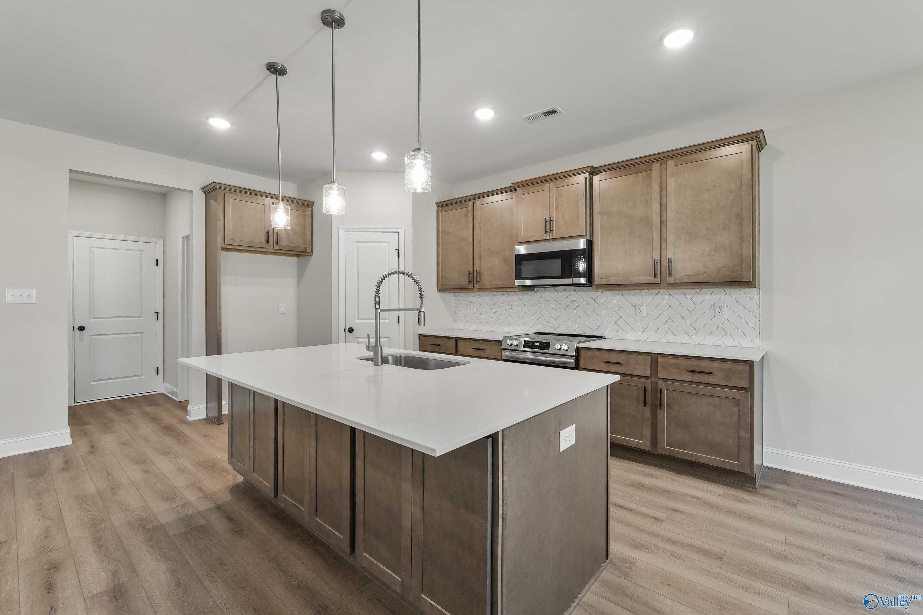 Modern kitchen with white quartz island, shaker cabinets, stainless appliances in Davidson Homes Montgomery C, Decatur AL