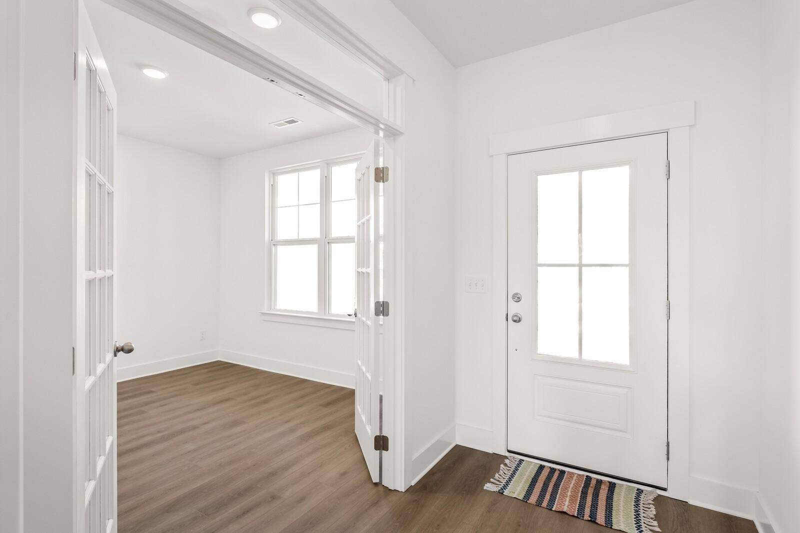 Bright entryway with white walls, hardwood floors, French doors, and glass-paneled entry in Davidson Homes The Ash A, Gallatin, TN