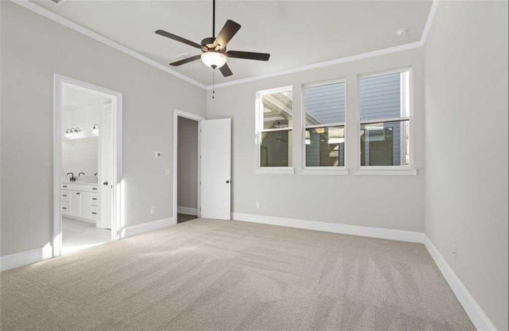 Bright bedroom featuring ceiling fan, three large windows, and en-suite bath in Davidson Homes The Seaside A, Woodstock, GA