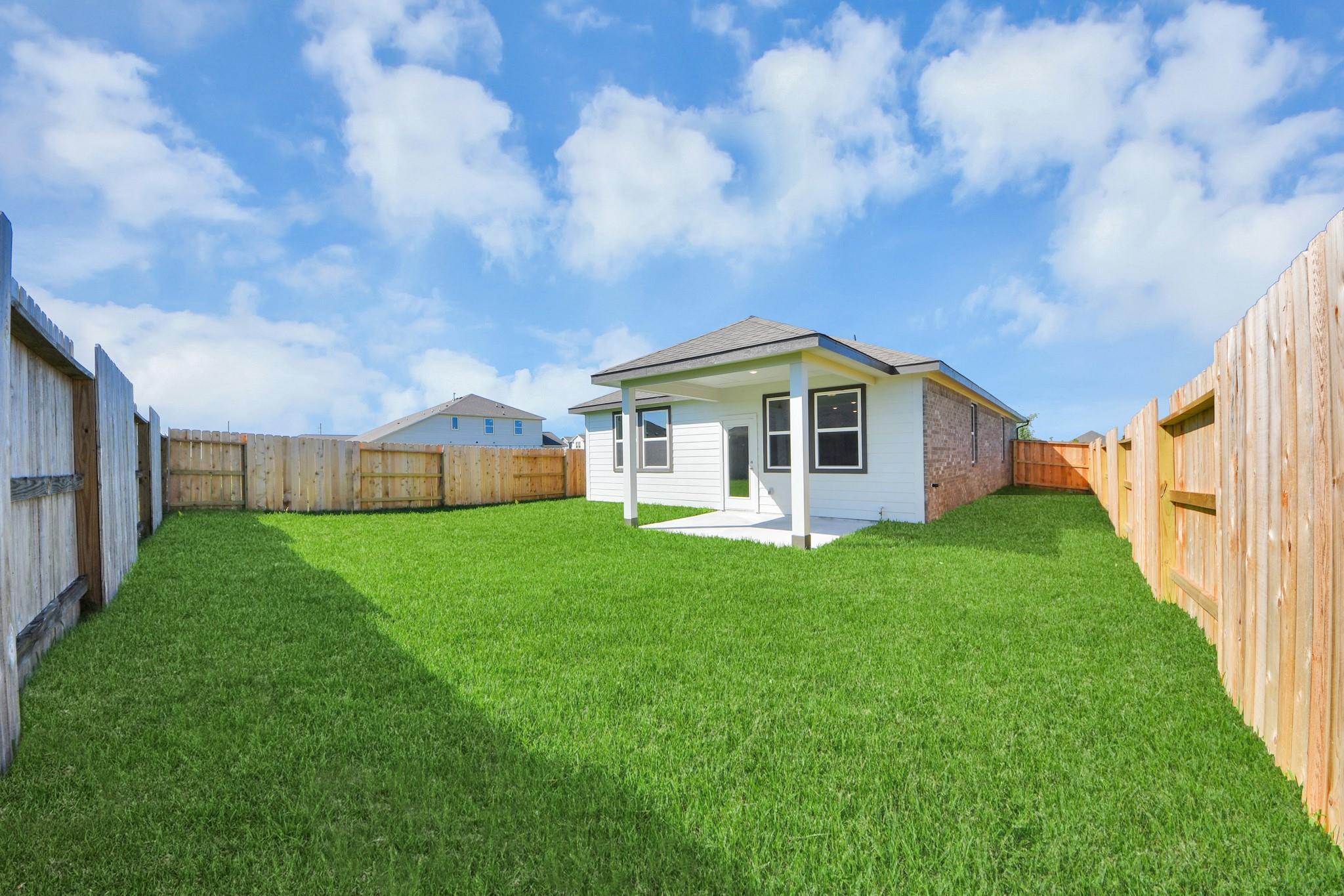 Covered patio and large private backyard of The Colorado G floor plan by Davidson Homes in Emberly, Beasley, Texas.