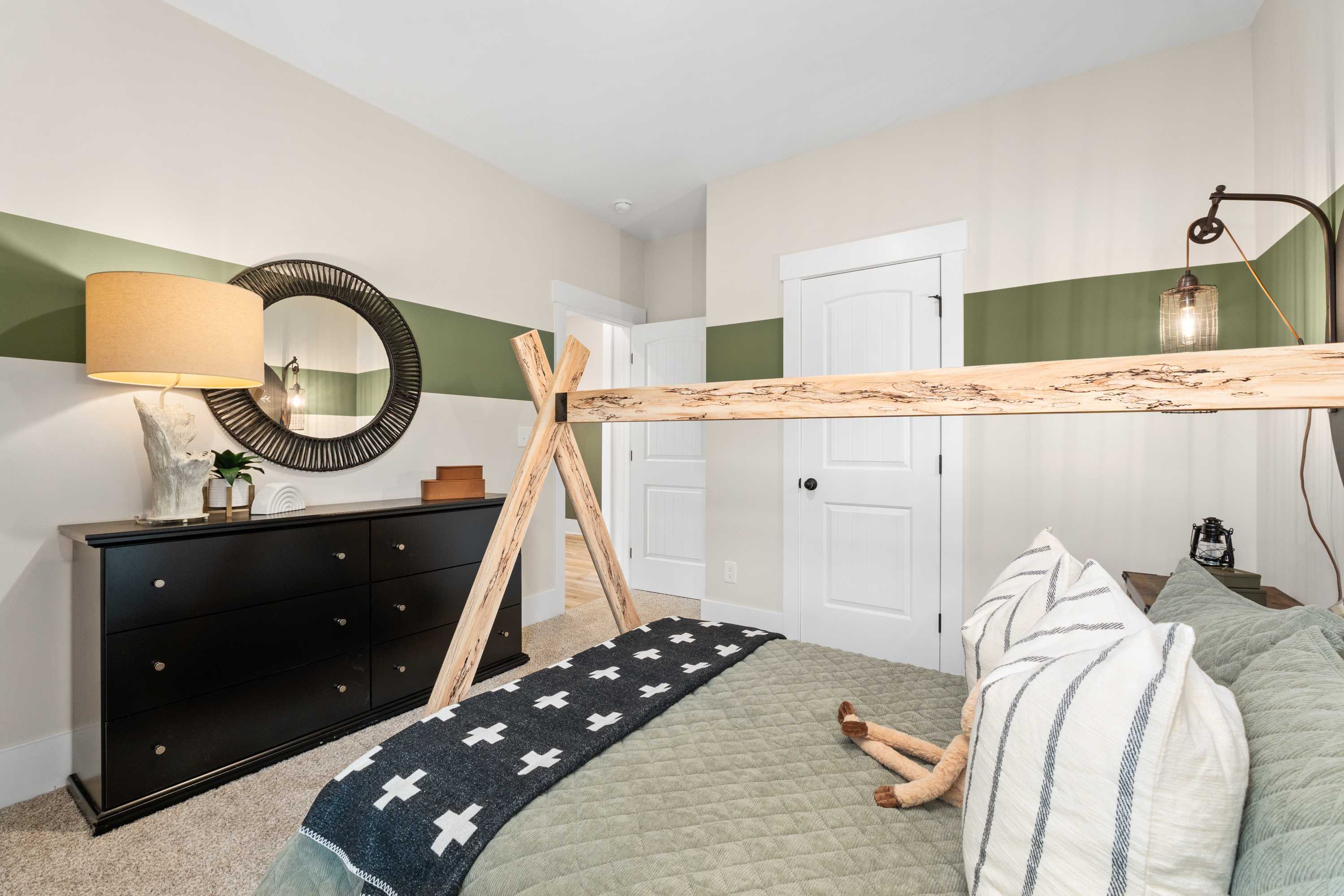 Cozy kids bedroom at Spragins Cove in Huntsville AL featuring wooden teepee bed frame, green accent wall, black dresser