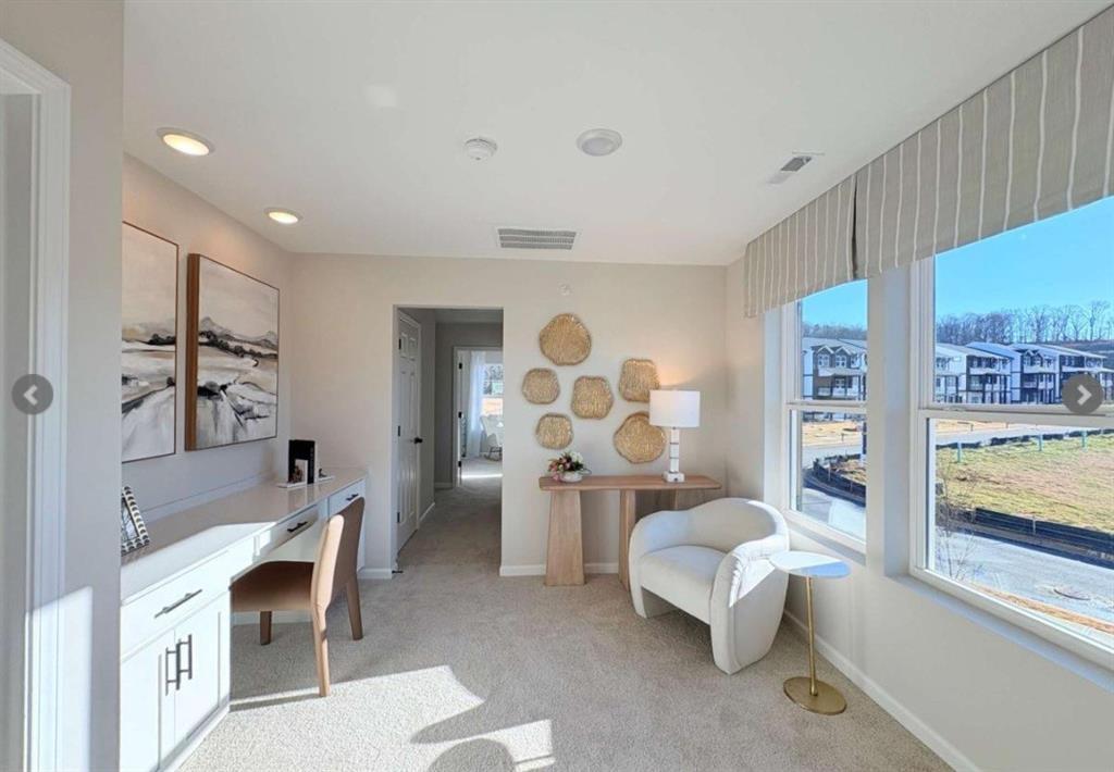 Modern home office with desk, white armchair, woven decor, and large windows in Davidson Homes The Durham D, Cumming, Georgia