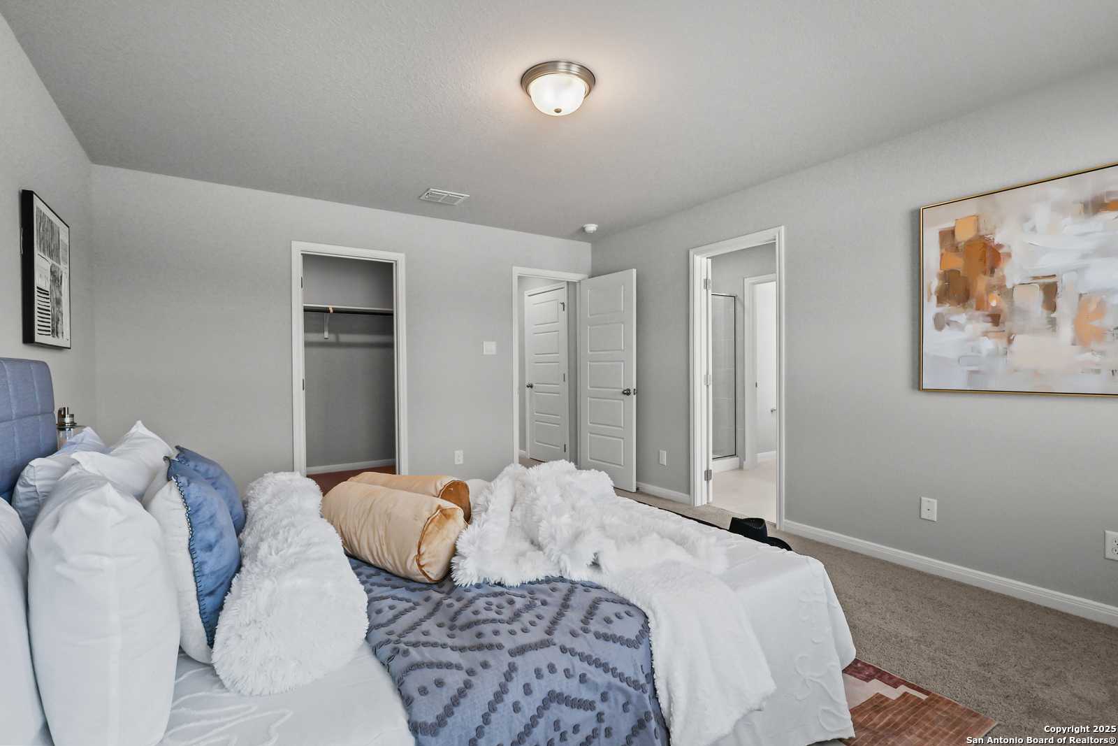 Cozy secondary bedroom with queen bed, blue duvet, orange accents, walk-in closet, en-suite bath in Davidson Homes The Gillian C, San Antonio