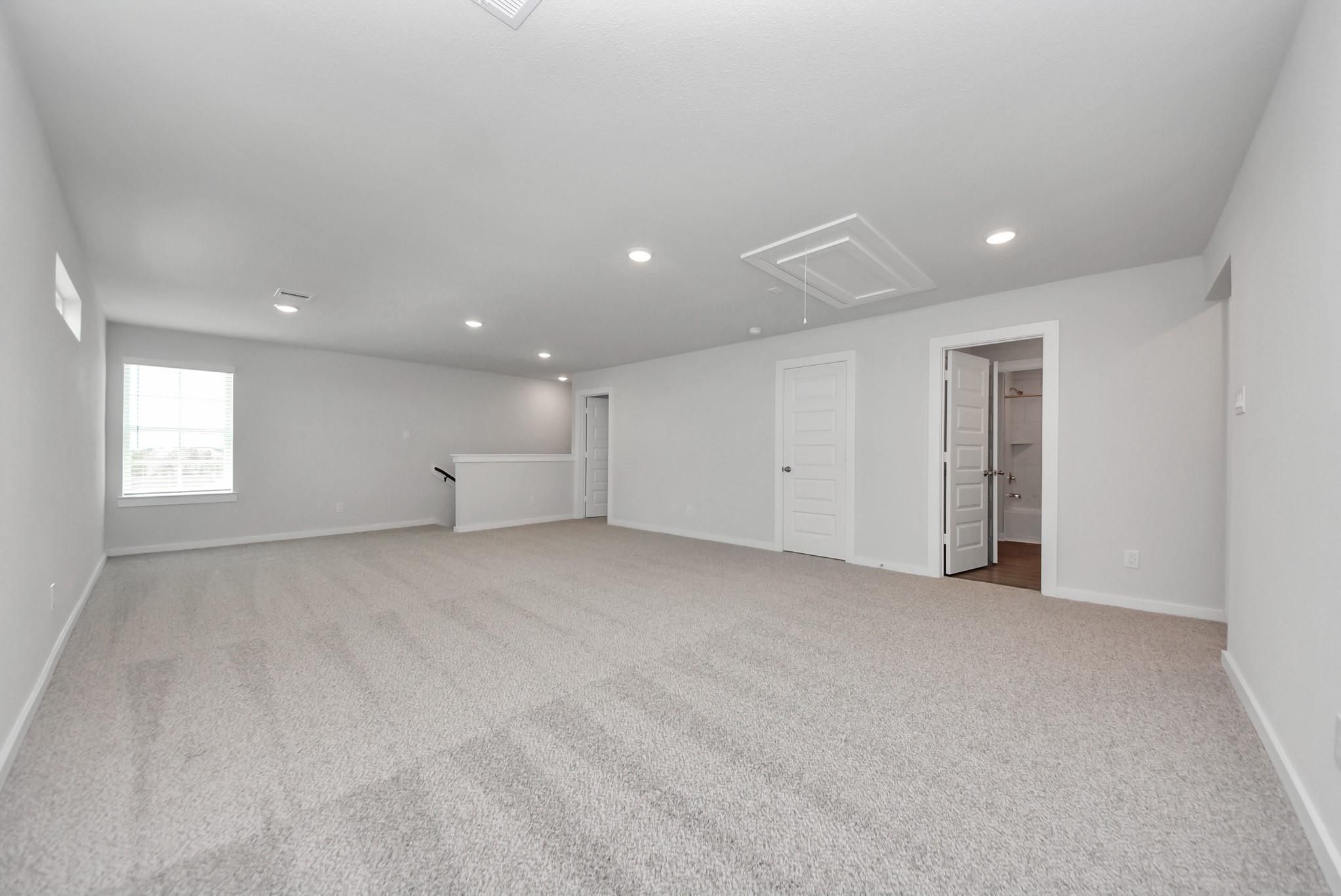 Spacious upstairs game room with carpet and recessed lighting in Davidson Homes San Marcos E plan, Emberly, Beasley, Texas