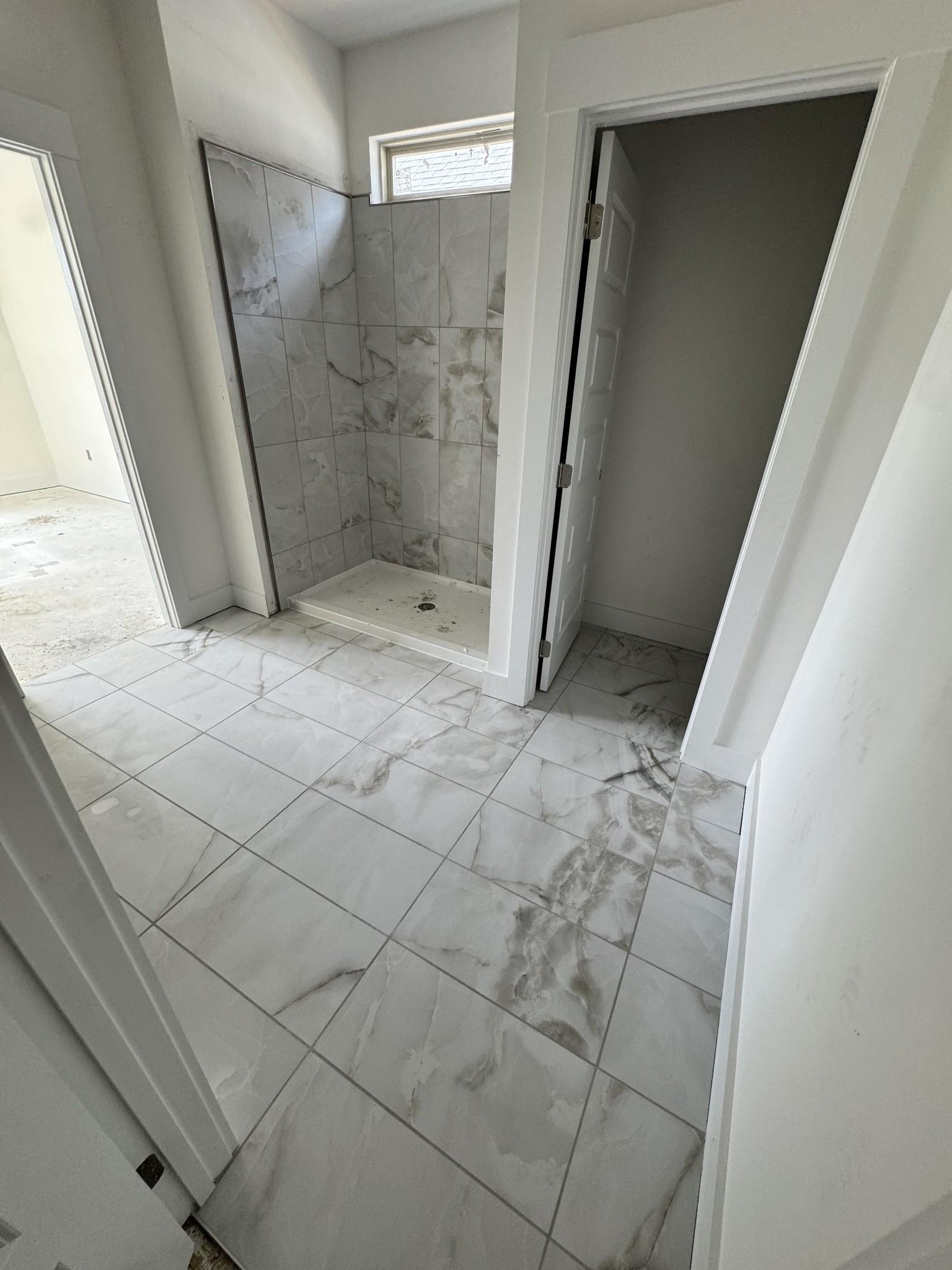 Elegant master bathroom featuring marble-patterned tiled walk-in shower and window in Davidson Homes The Prairie C, Gallatin, TN