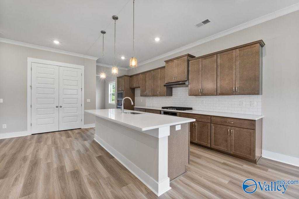 Modern kitchen with shaker wood cabinets, white quartz island, subway tile backsplash in The Oxford 5-bedroom home, Owens Cross Roads, AL