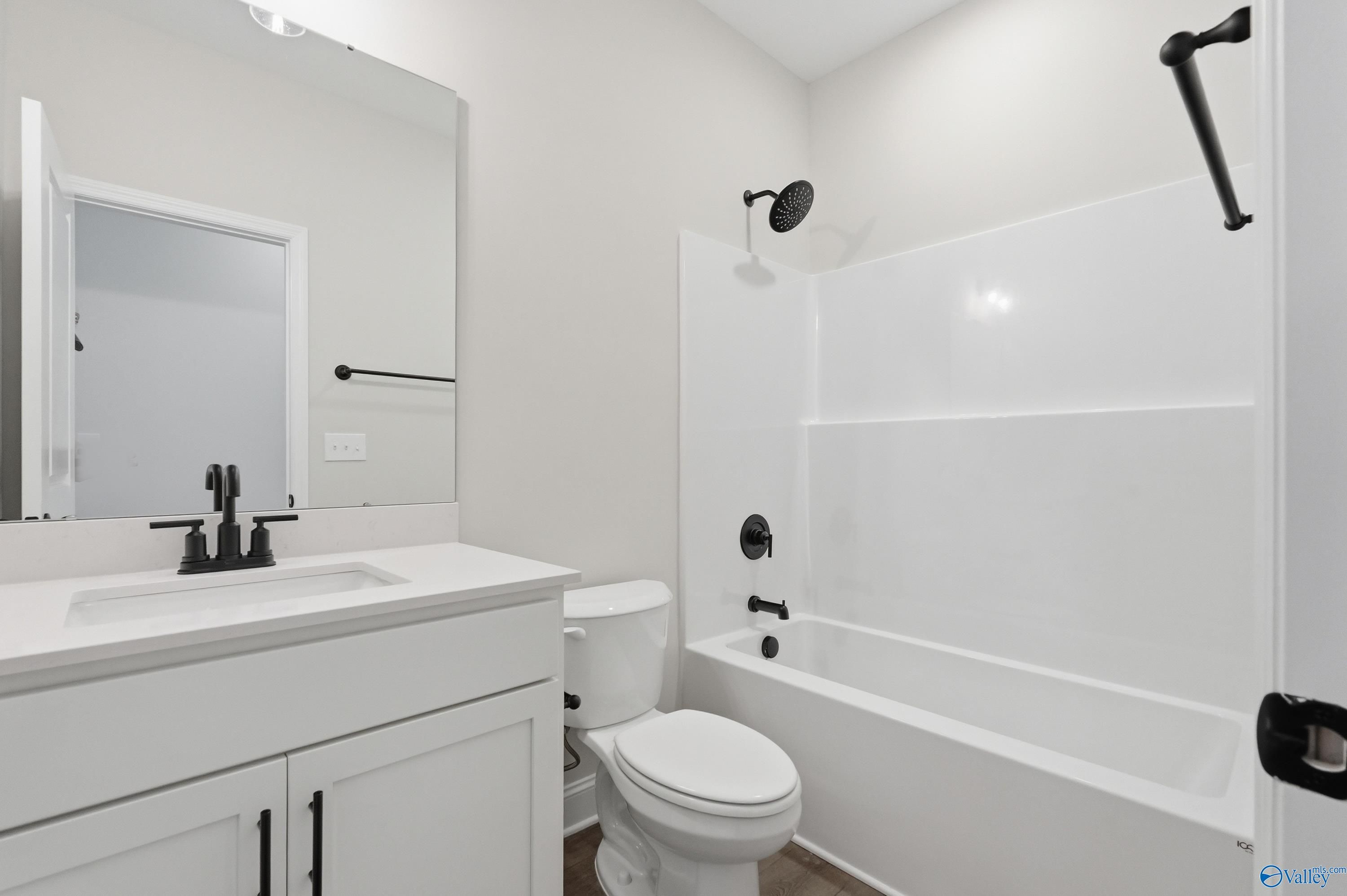 Modern secondary bathroom with white tub-shower combo, black fixtures, and vanity in Davidson Homes The Rockford B, Athens AL