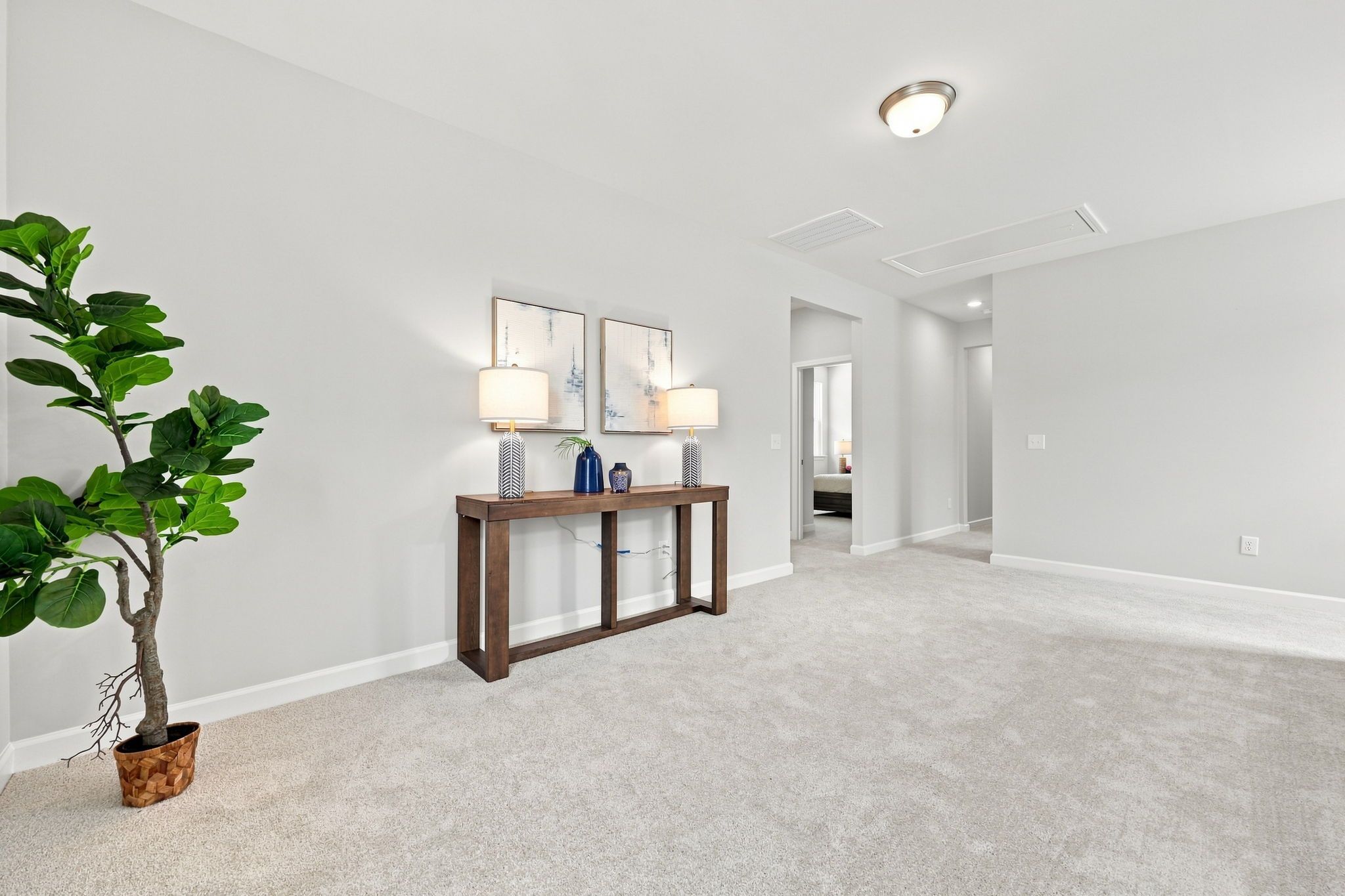 Spacious hallway with neutral carpeting at Bradshaw Farms in Mt. Juliet, TN, featuring a wooden console table and decor.