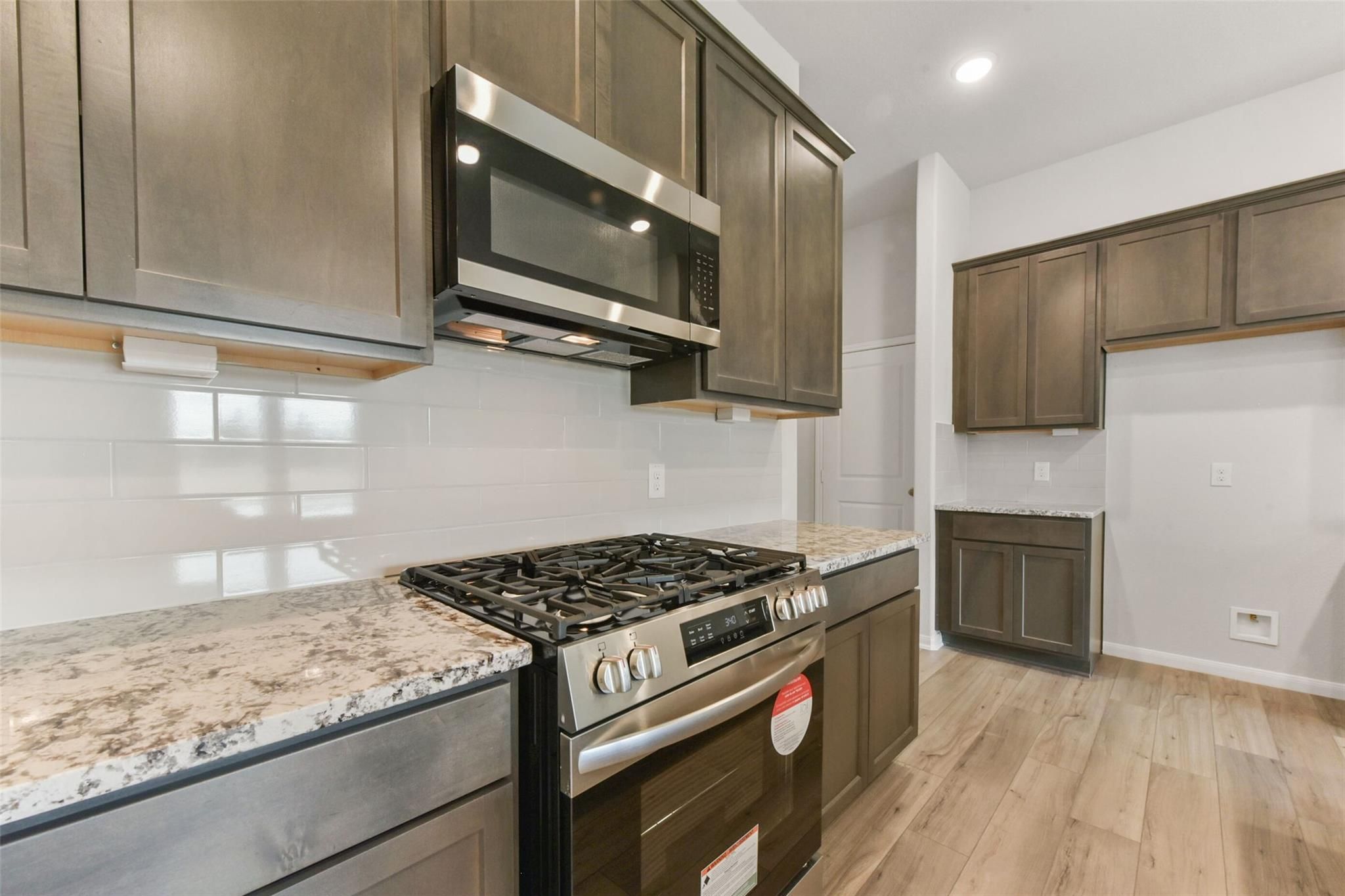 Modern kitchen featuring stainless steel appliances, granite countertops, subway tile backsplash in Davidson Homes The Laguna B, Magnolia, Texas