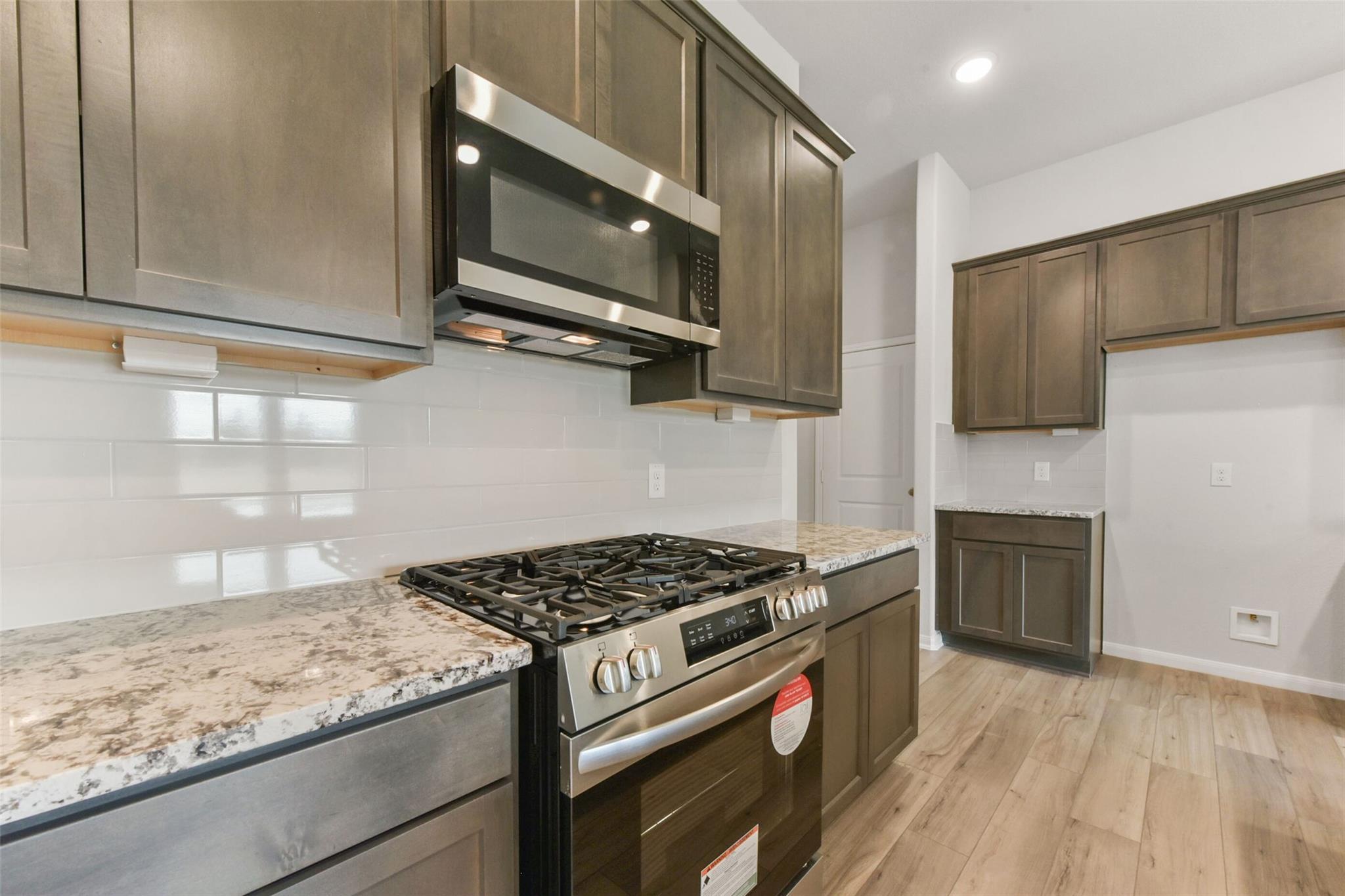 Modern kitchen featuring stainless steel appliances, granite countertops, subway tile backsplash in Davidson Homes The Laguna B, Magnolia, Texas