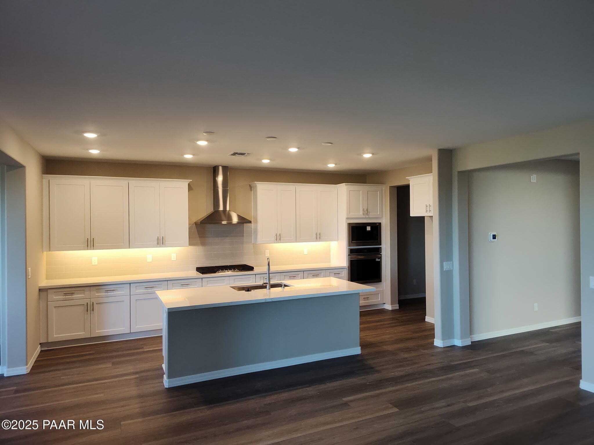 Modern white kitchen with central island, stainless steel range and hood in Davidson Homes The Inspiration A, Prescott Valley, Arizona