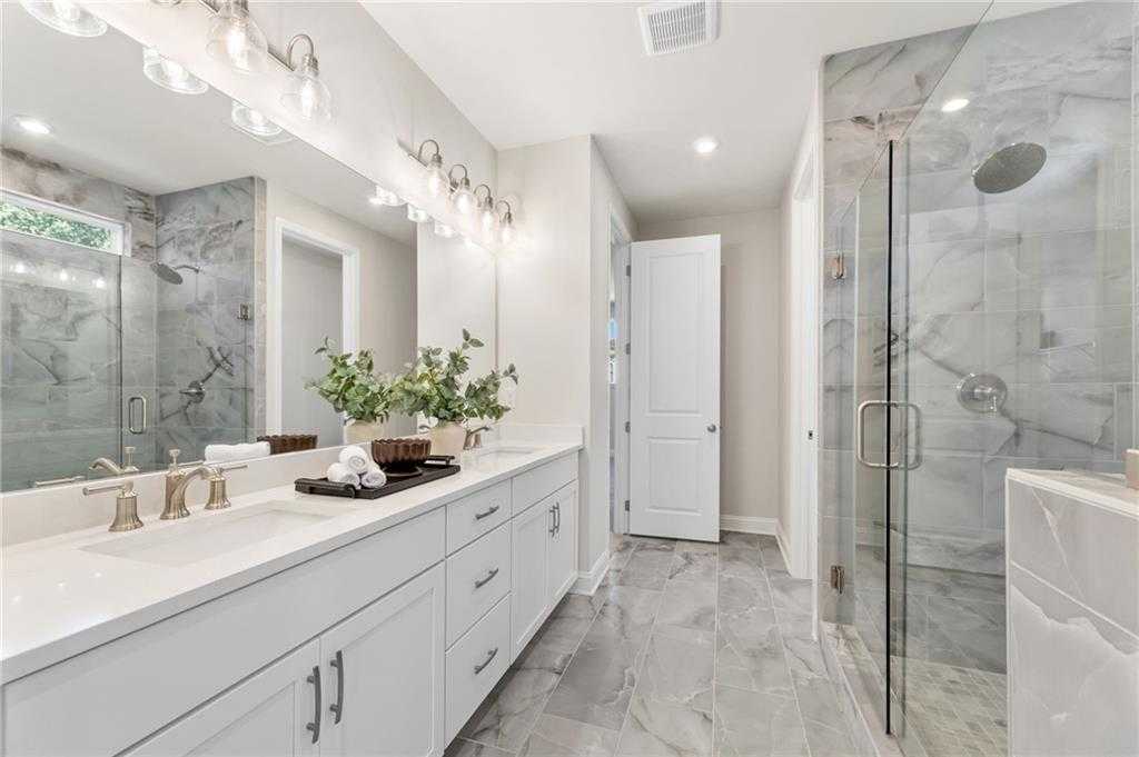 Luxurious primary bathroom with double marble vanity, frameless glass shower, and modern fixtures in Davidson Homes The Danbury C, Buford, GA