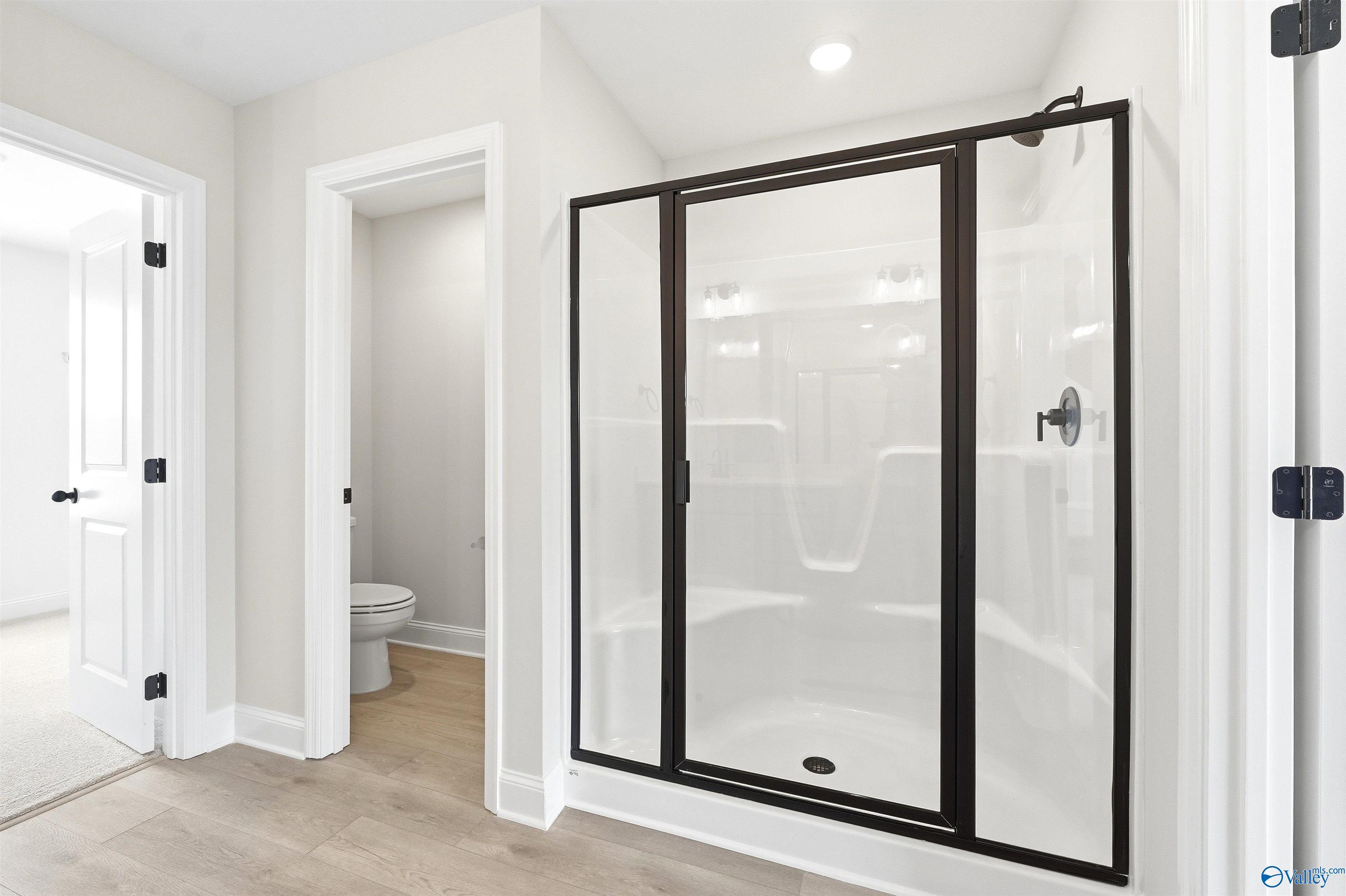 Modern walk-in shower with black frame and separate water closet in The Shelby A floor plan at Wood Trail, Toney, Alabama.