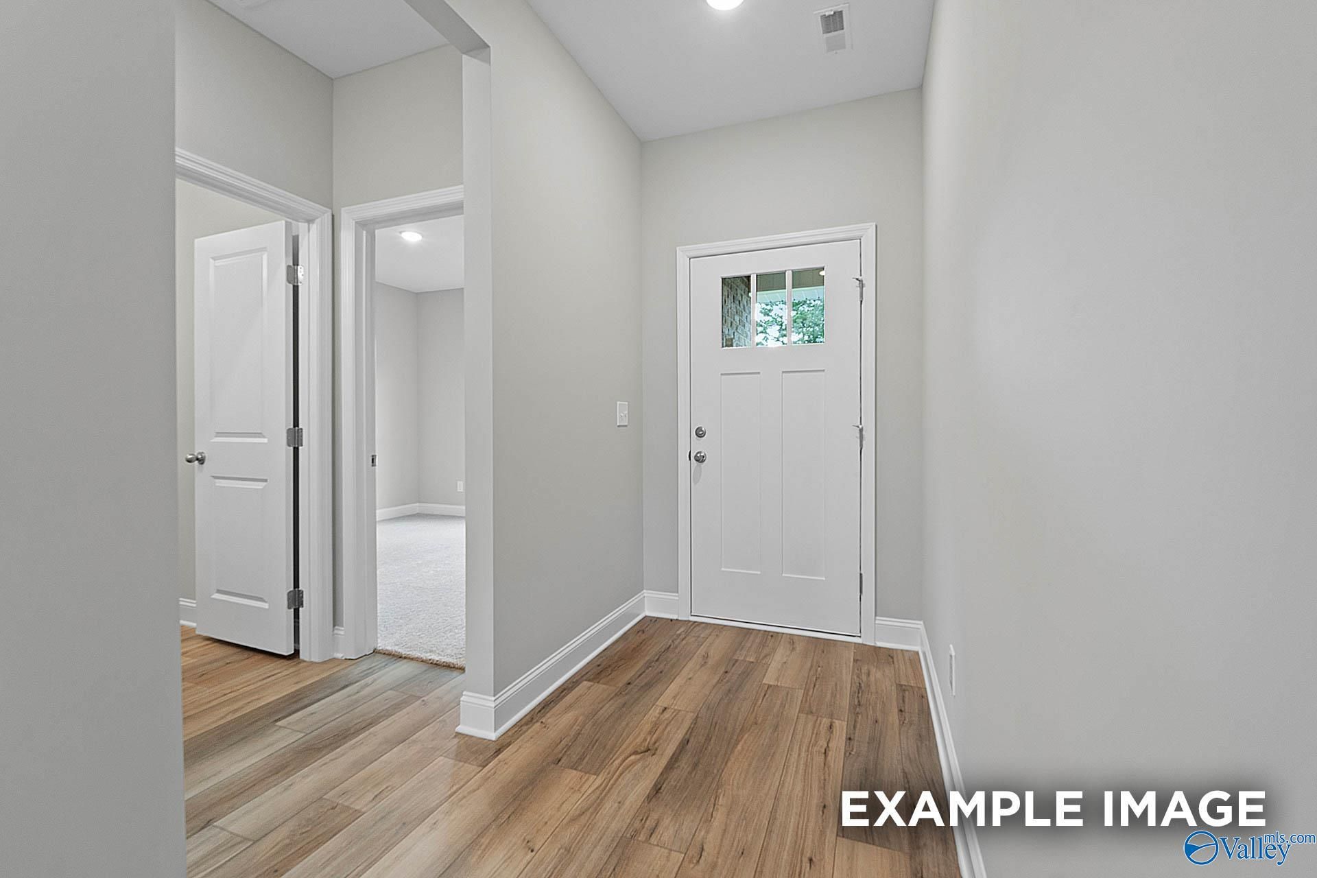 Bright hallway with hardwood floors, white doors, and light gray walls in 3-bedroom The Franklin E home, Hazel Green, Alabama