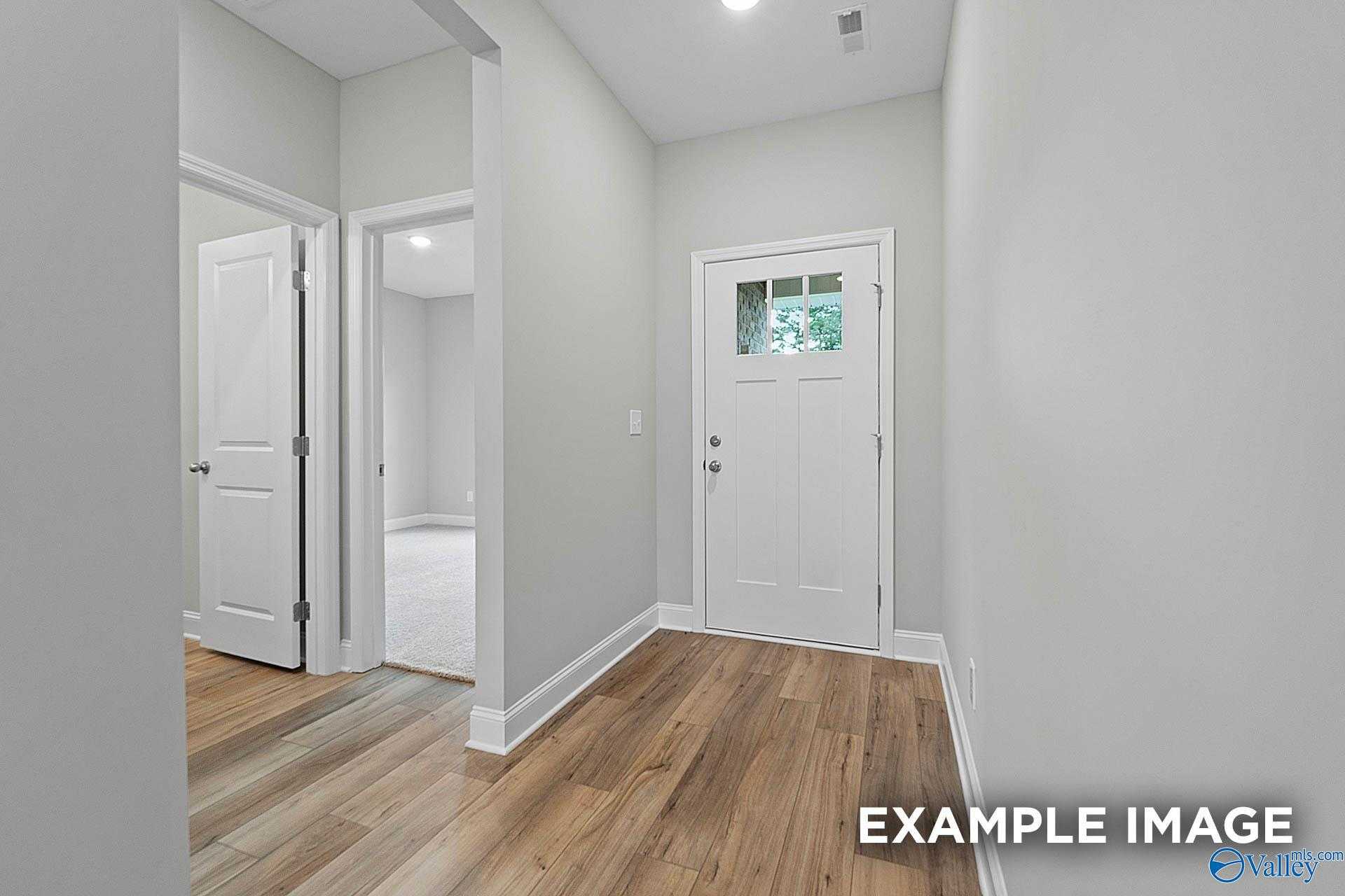 Bright hallway with hardwood floors, white doors, and light gray walls in 3-bedroom The Franklin E home, Hazel Green, Alabama