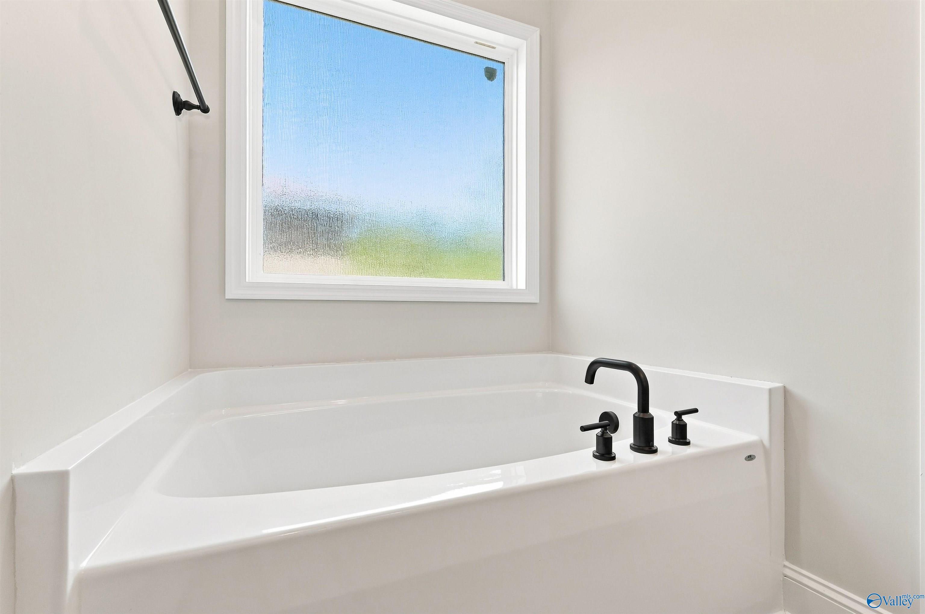 Modern soaking tub with matte black faucet in the master bathroom of The Daphne floor plan in Spragins Cove, Huntsville.