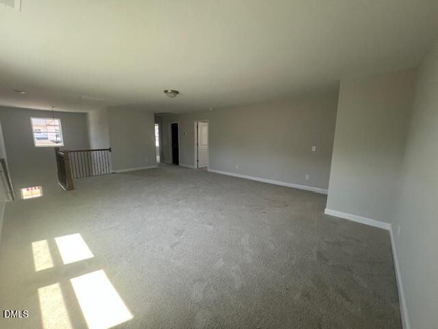 Spacious upstairs loft with gray walls, carpeted floor, and balcony railing in The Adalynn A 4-bedroom home, Lillington, NC