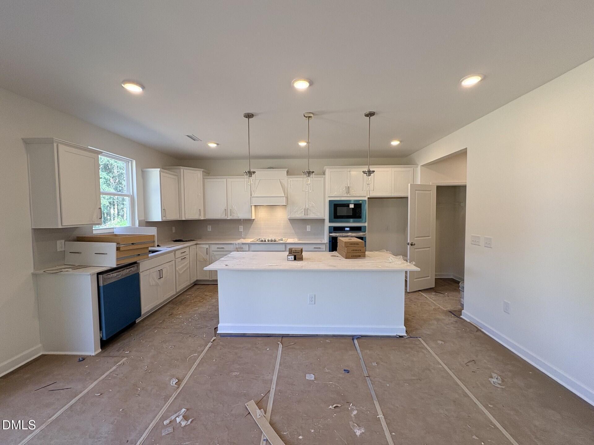 New construction kitchen with white cabinets, island, and stainless appliances in Davidson Homes The Hickory II B, Zebulon NC