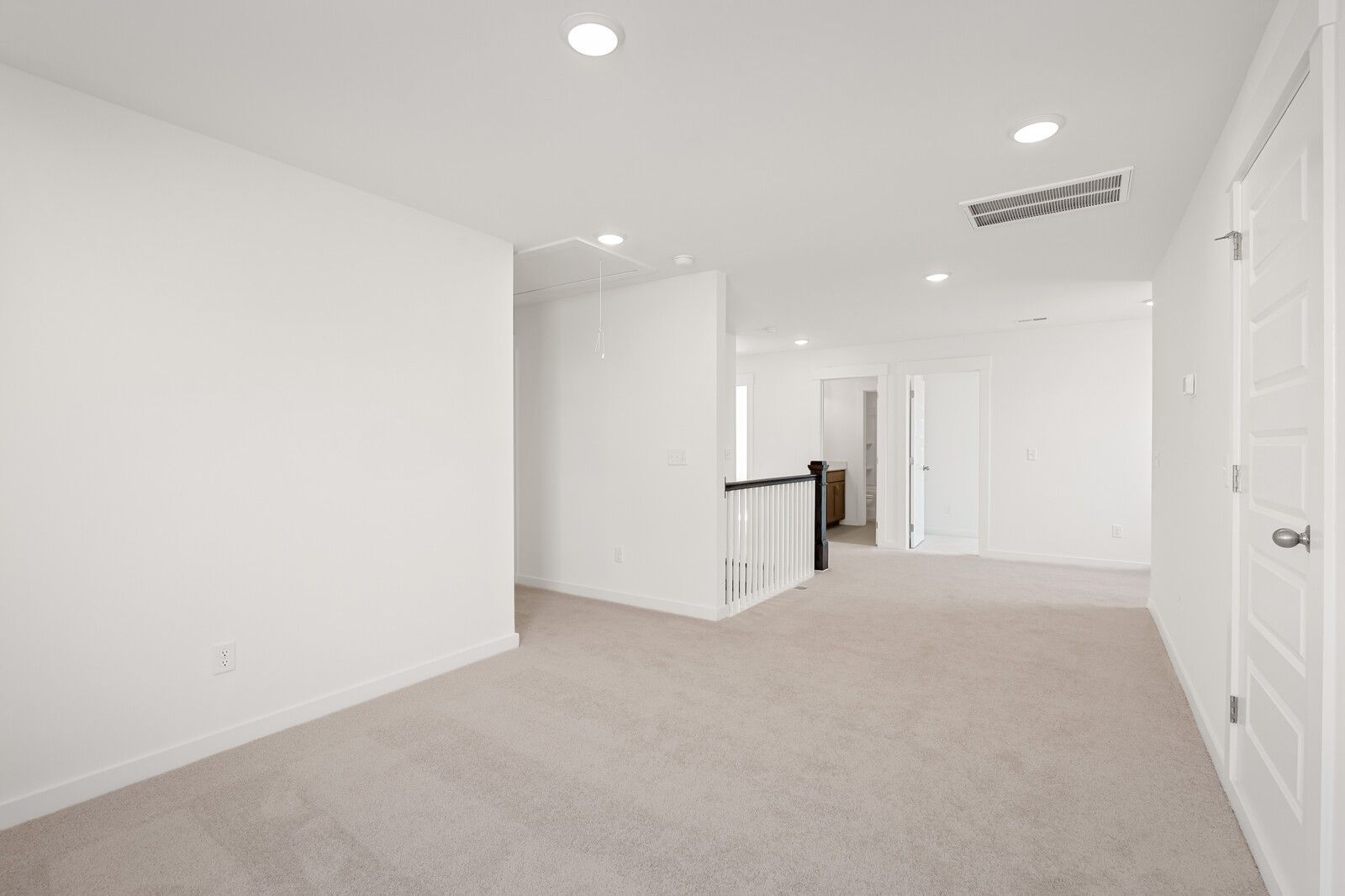 Spacious upstairs loft with white walls, beige carpet, recessed lights, and balcony railing in Davidson Homes The Ash C, Mt. Juliet