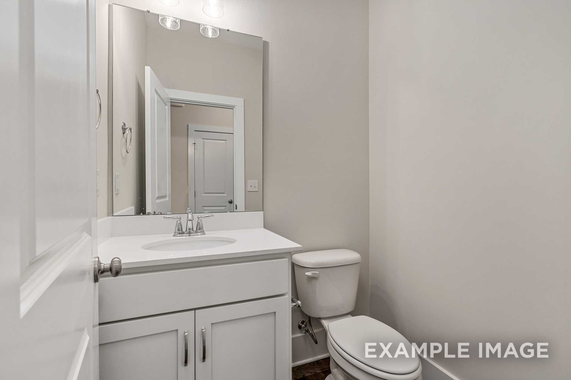 Modern powder room in The Rockford home by Davidson Homes featuring white vanity, sink, large mirror, and toilet