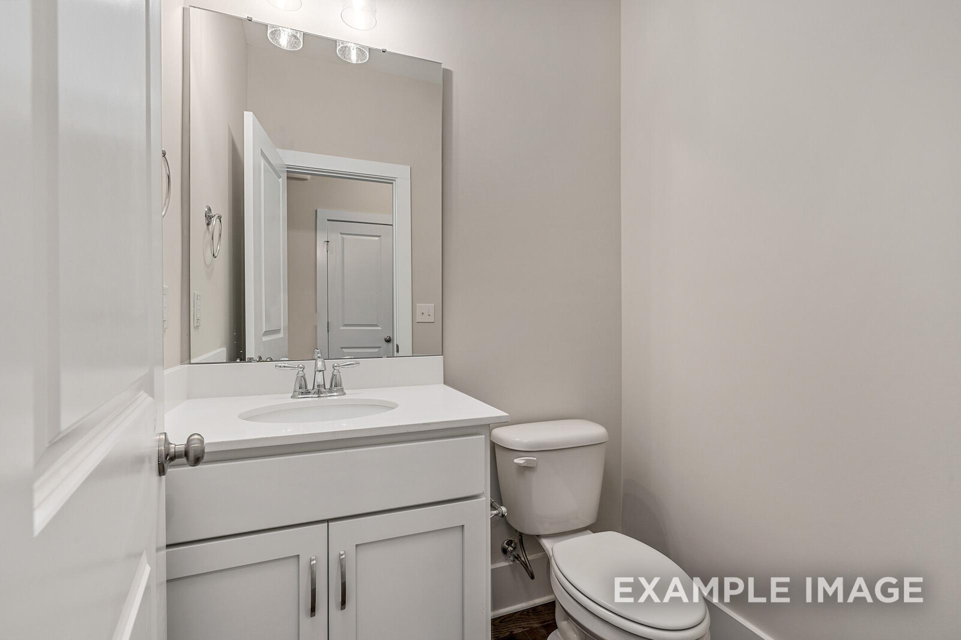 Modern powder room in The Rockford floor plan by Davidson Homes featuring white vanity, sink, toilet, and lighted mirror