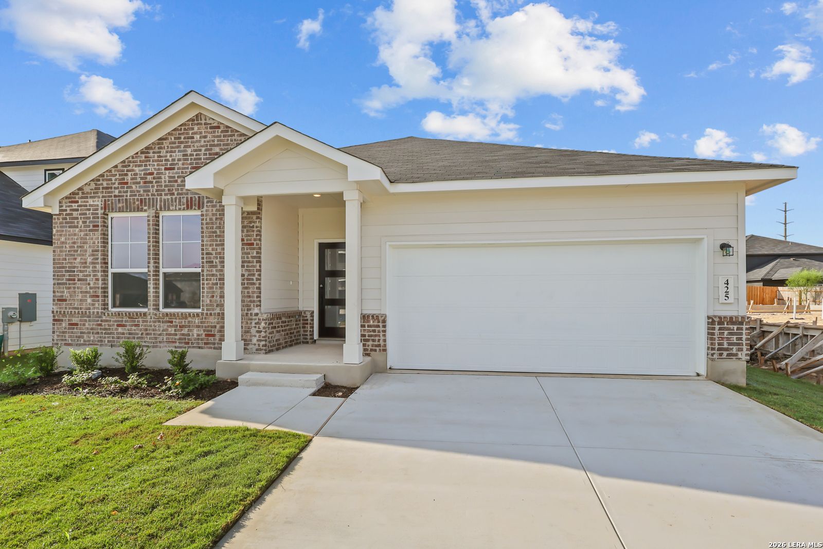 Brick and white 1-story new home with covered porch and 2-car garage at Hannah Heights, Seguin, Texas by Davidson Homes