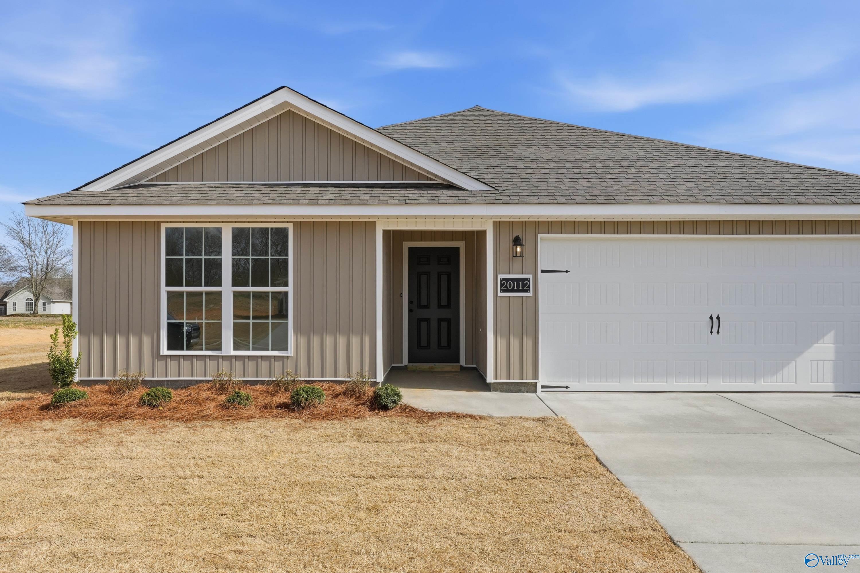 Modern beige single-story home with gabled roof, large window, 2-car garage, and front landscaping in Chapel Hill, Athens, Alabama
