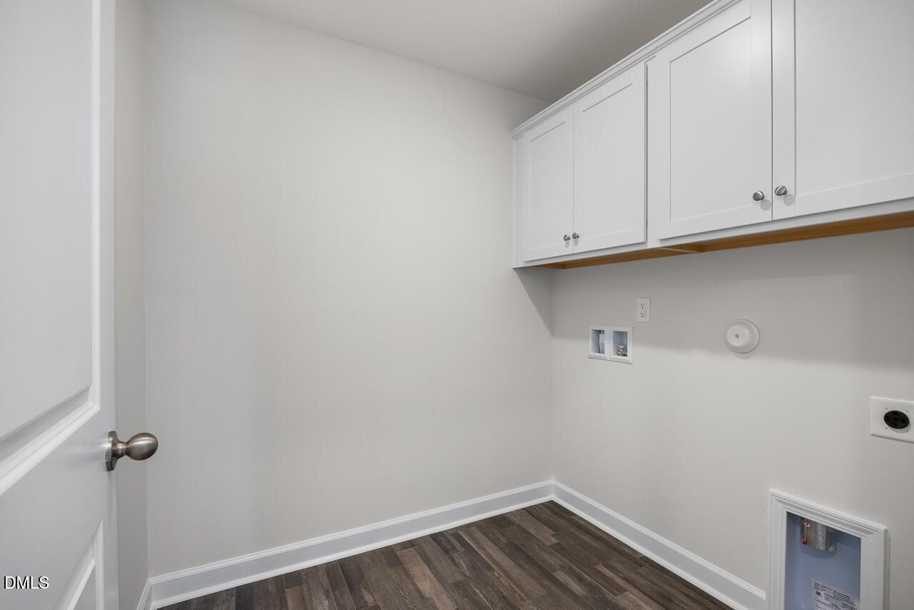 Laundry room with white cabinets and wood-style flooring in The Mitchell Interior floor plan at Forestville Yard Townhomes.