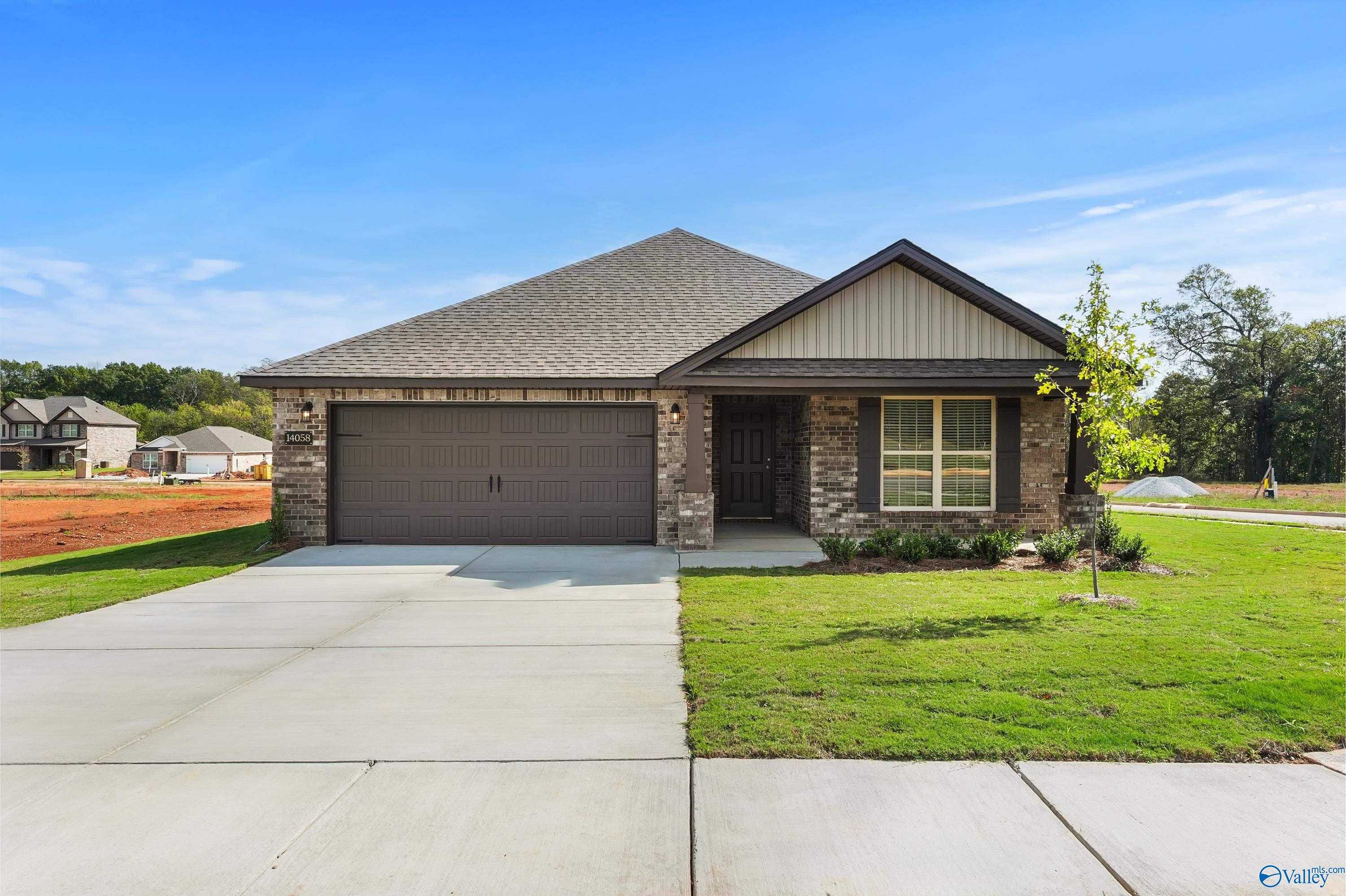 Modern single-story 4-bedroom home with 2-car garage, stone accents, and lush front yard in The Meadows, Athens, Alabama