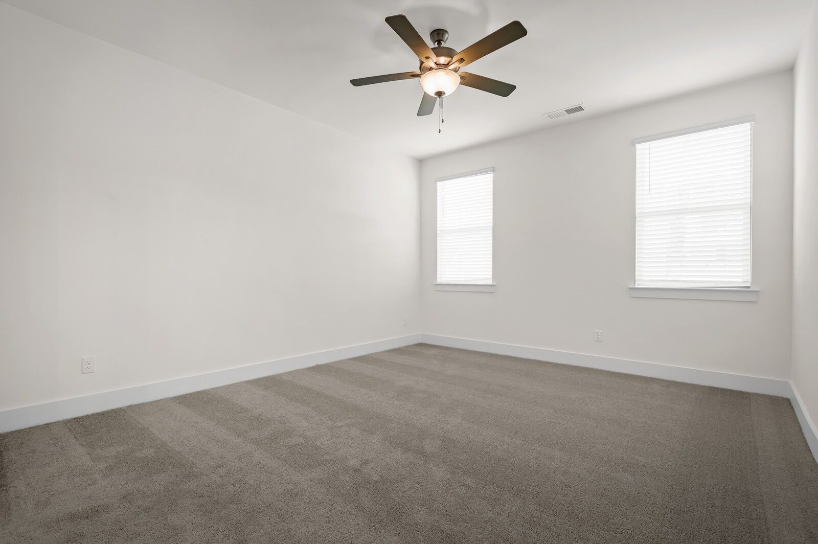 Spacious secondary bedroom with ceiling fan and plush carpeting in The Ash A floor plan at Woods Crossing, Gallatin, TN.