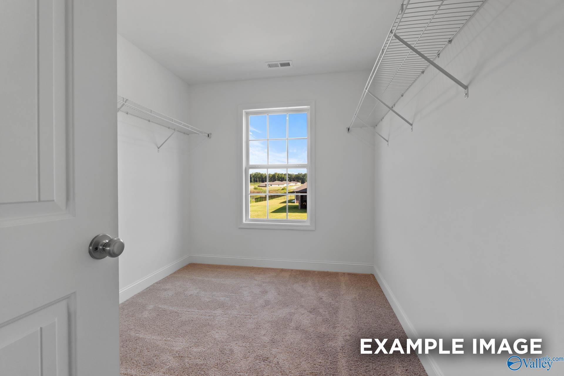 Bright walk-in closet with wire shelving, hanging rods, and window overlooking fields in Davidson Homes Shelby B, New Market, Alabama