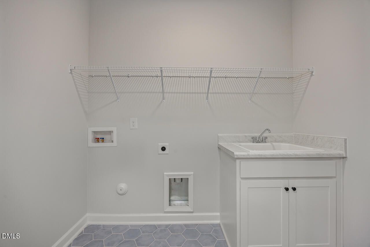 Laundry room with utility sink, white cabinets, and wire shelving in Birch II E floor plan at Sage on North Main.