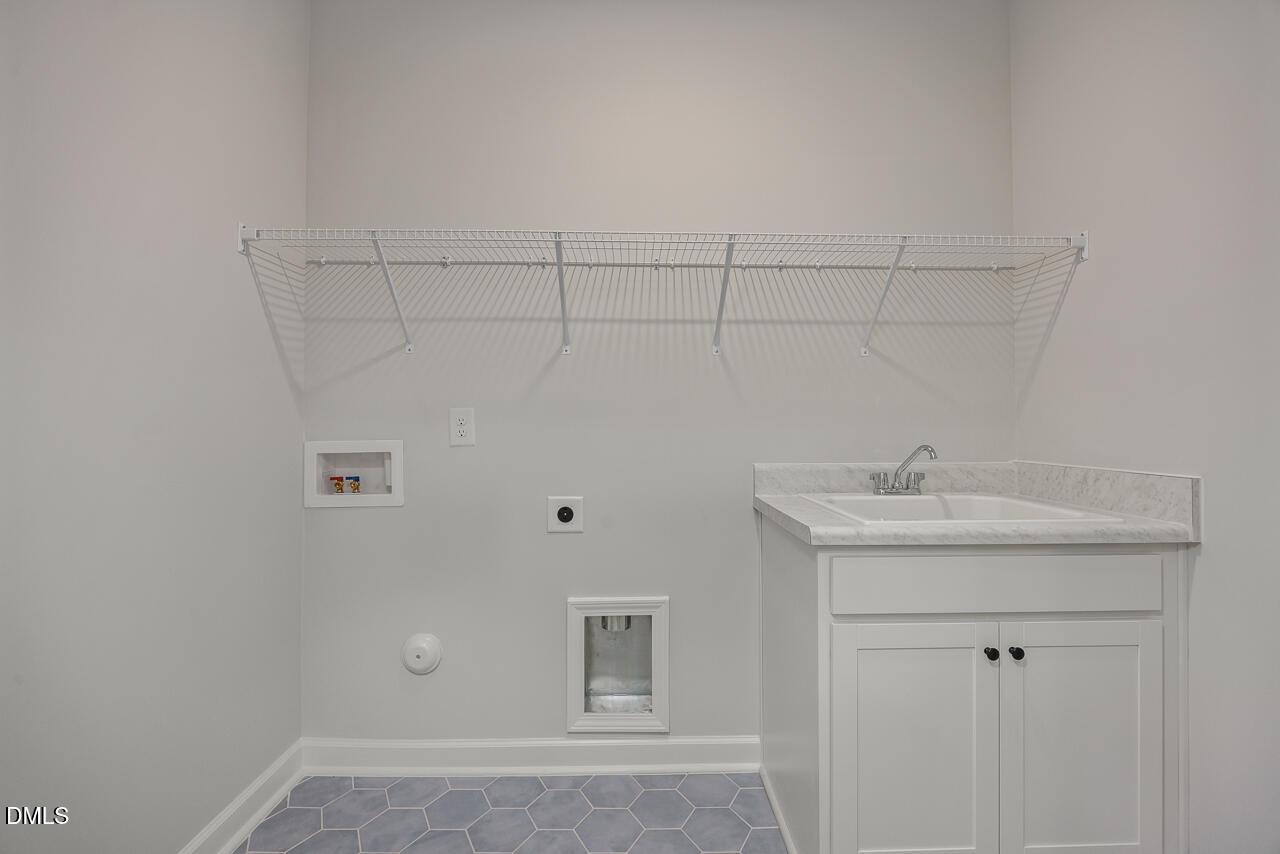 Laundry room with utility sink, white cabinets, and wire shelving in Birch II E floor plan at Sage on North Main.