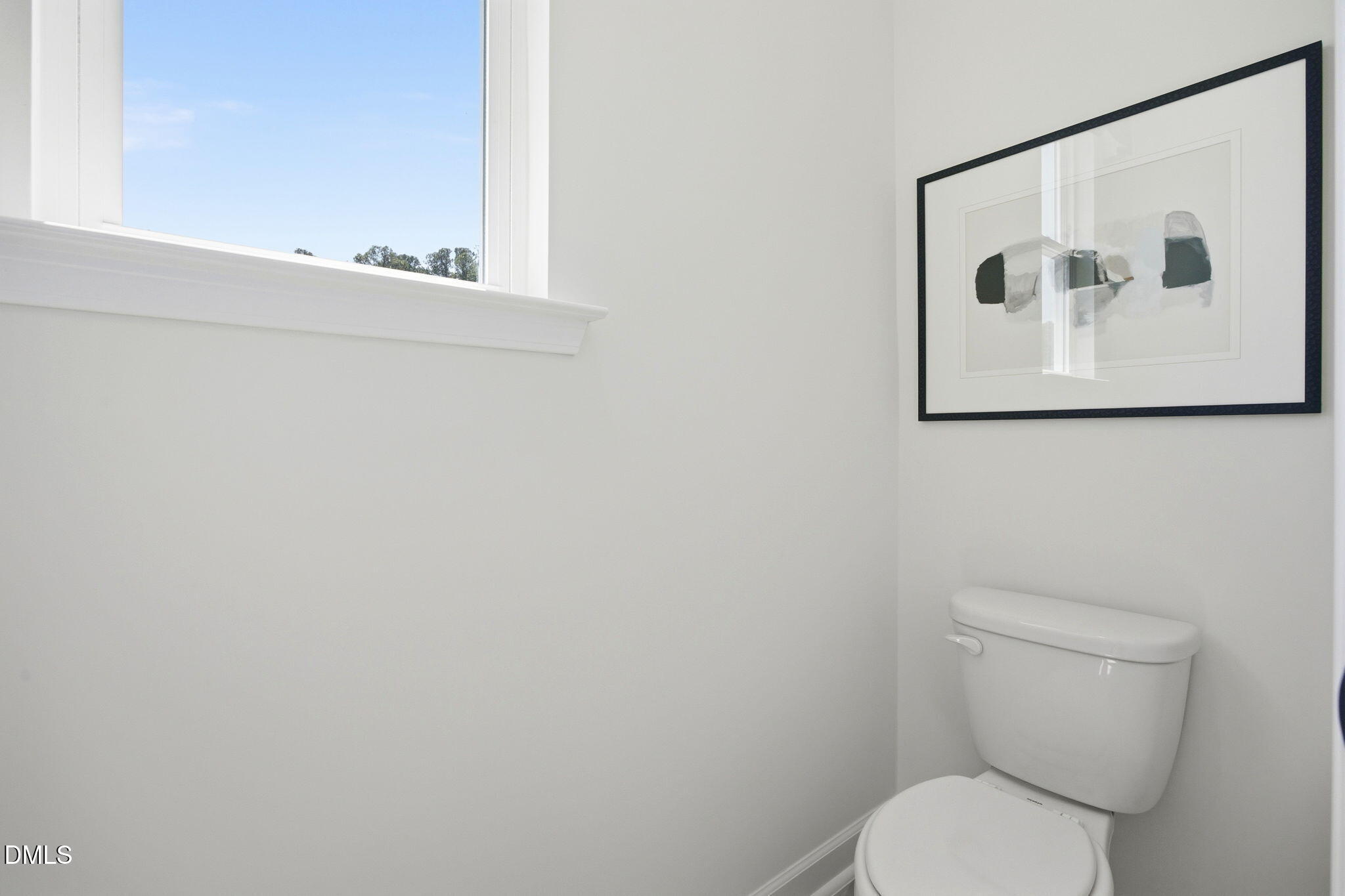 Modern powder room with wall art and window in The Ashport M floor plan at Wendell Ridge, Wendell, North Carolina.