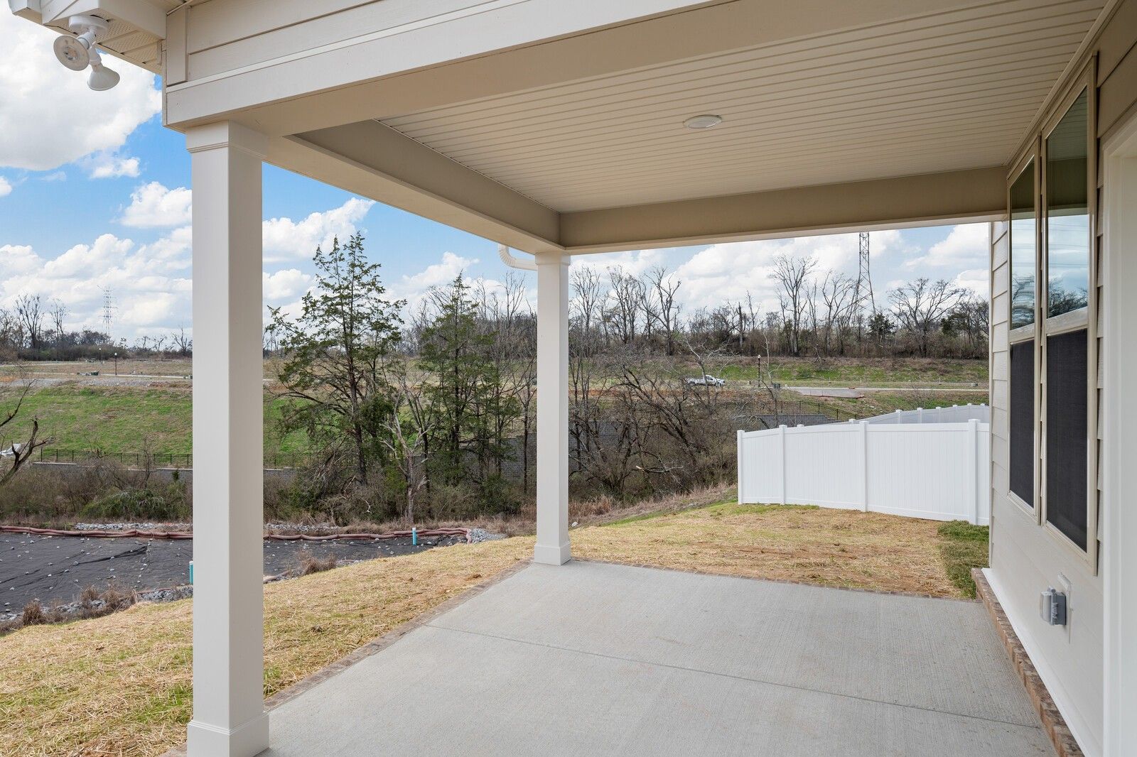 Covered back patio with concrete deck overlooking wooded yard and fence in Davidson Homes The Willow C, Woods Crossing, Gallatin, Tennessee