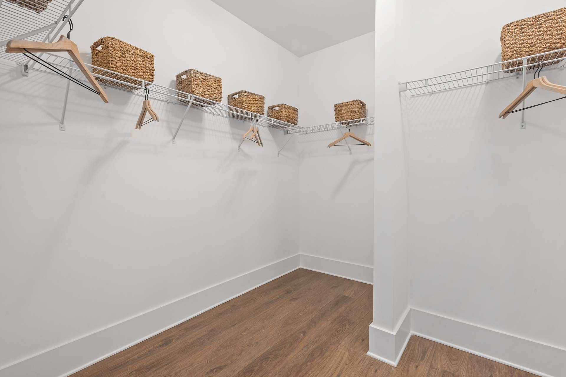 Spacious walk-in closet at Monteagle Cove in Owens Cross Roads Alabama by Davidson Homes featuring wire shelving wicker baskets hardwood floors