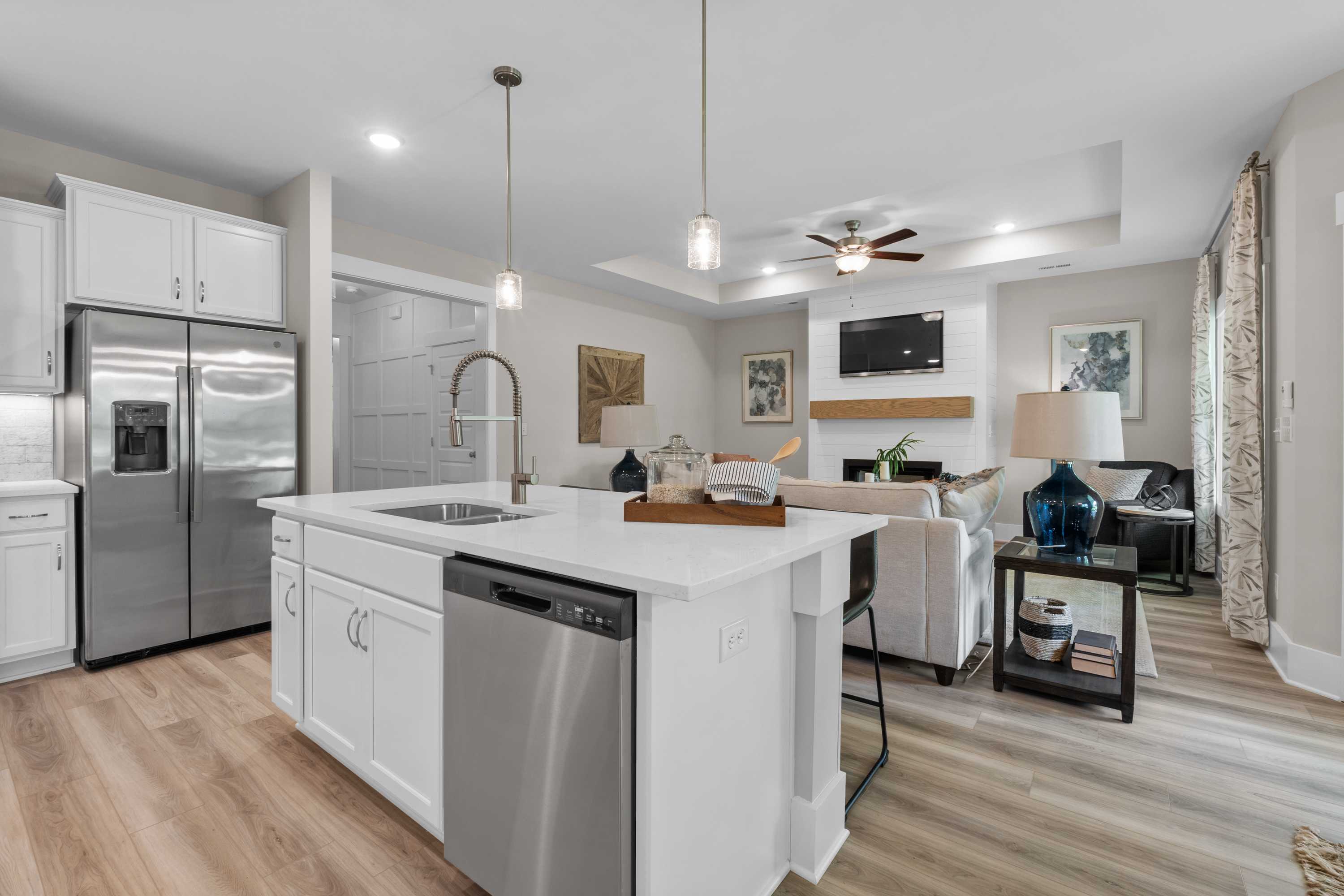 Open-concept kitchen and living room in The Highlands Arab Alabama with white island, stainless appliances, hardwood floors and cozy fireplace