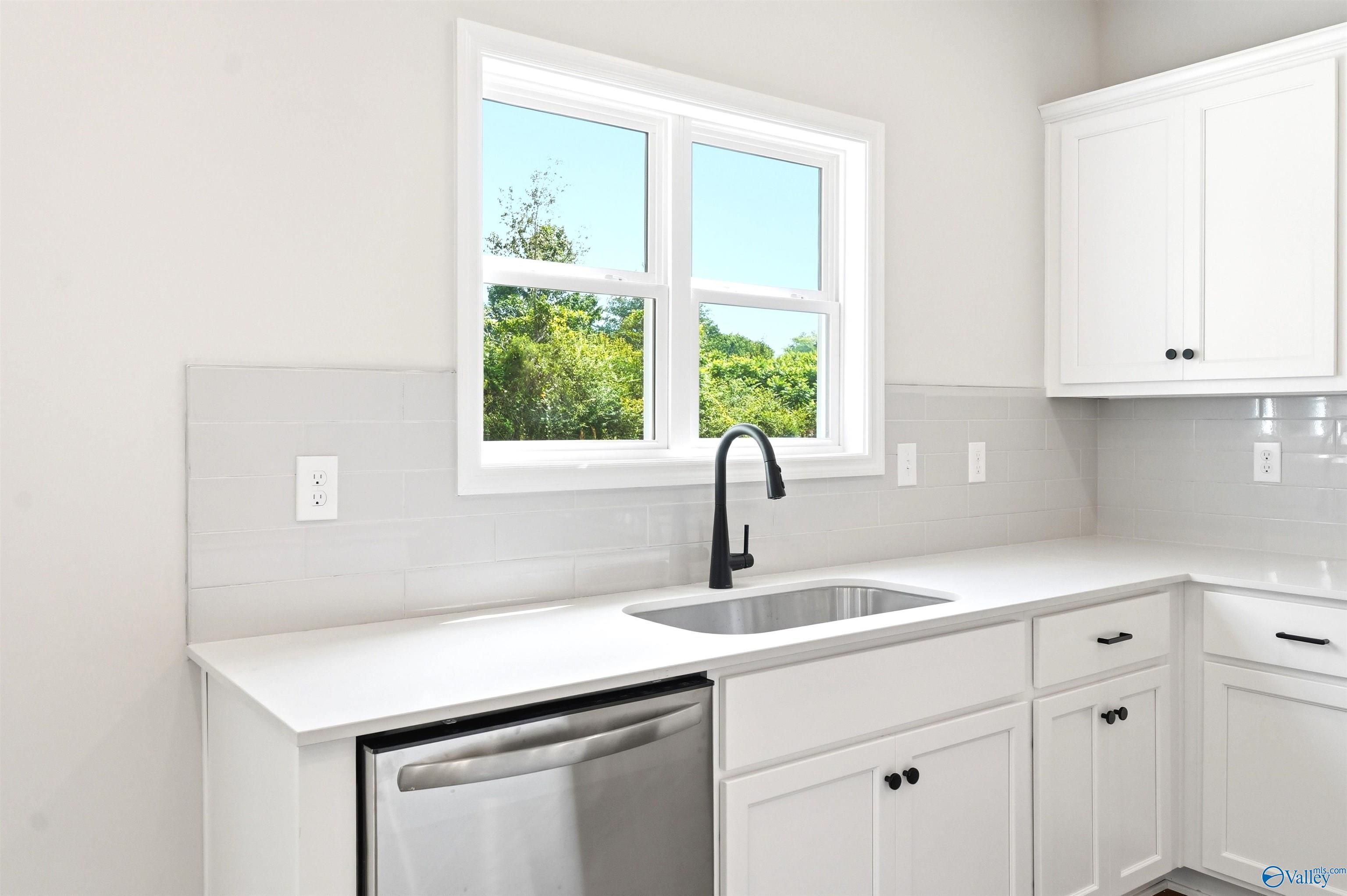 Modern kitchen sink with matte black faucet and white cabinets in The Chelsea D floor plan at Berry Cove, New Market, AL.