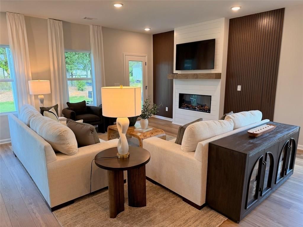 Modern great room with fireplace, mounted TV, and cream sofas in Davidson Homes Pinecrest J plan, Greene Farm, Cartersville, GA