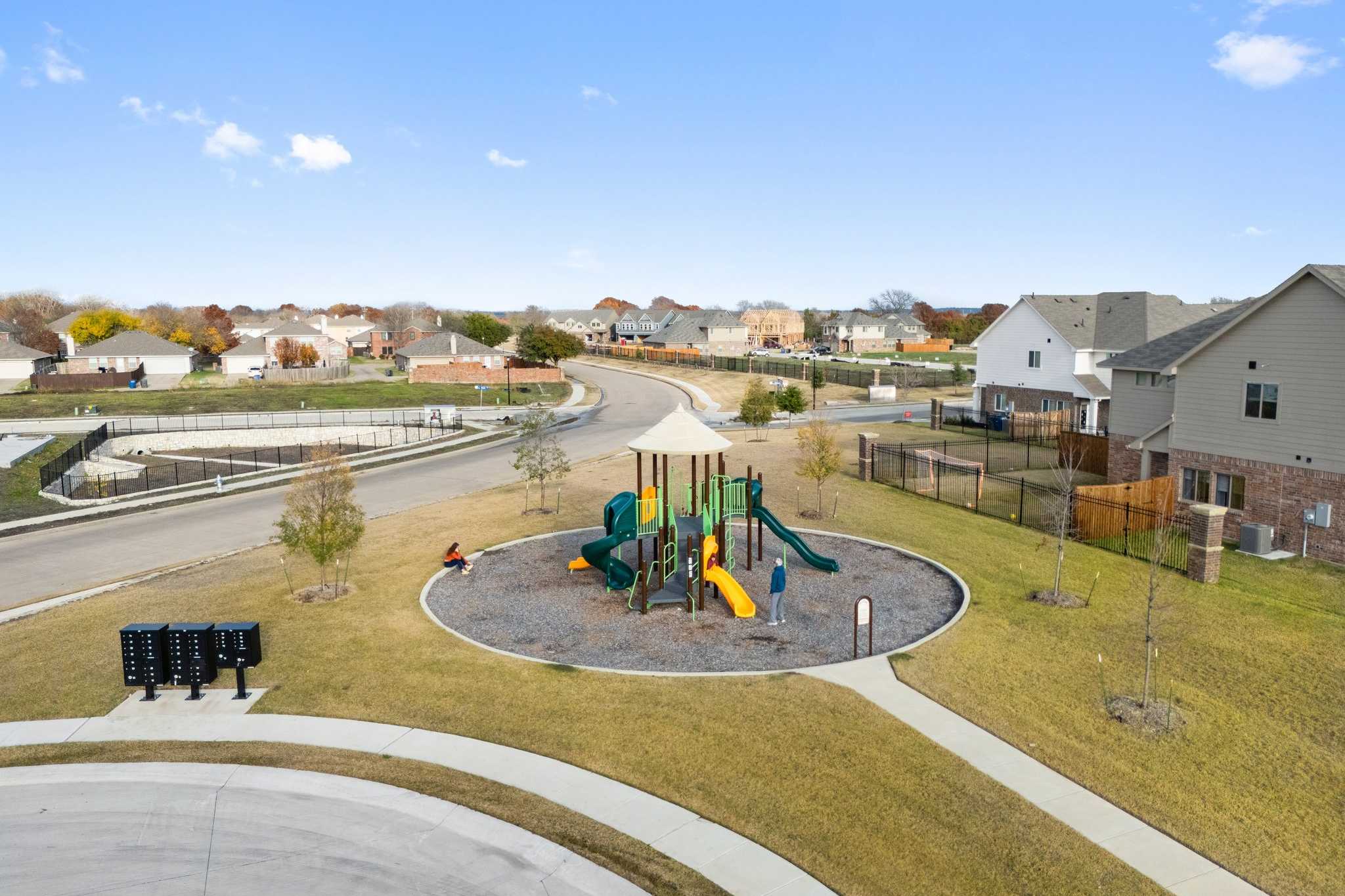 Children's playground at Lake Park Villas in Wylie TX with colorful slides, swings, rubber surfacing, and nearby suburban homes