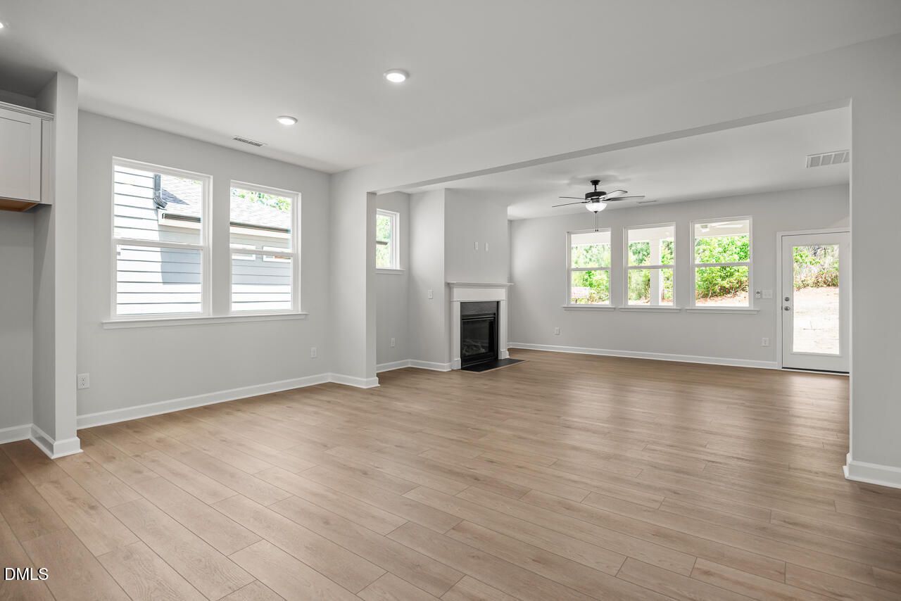 Open-concept living room with fireplace and hardwood floors in The Birch II E floor plan, Sage on North Main, Wake Forest.