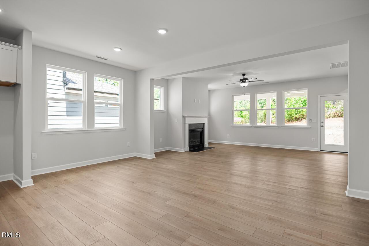 Open-concept living room with fireplace and hardwood floors in The Birch II E floor plan, Sage on North Main, Wake Forest.