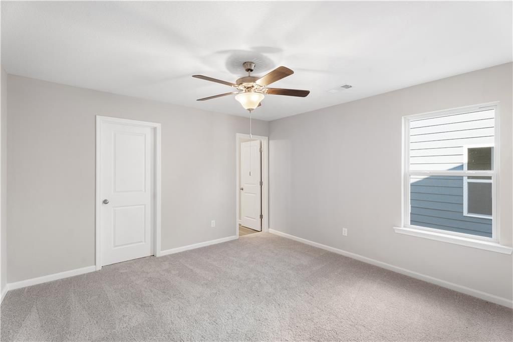 Spacious secondary bedroom with ceiling fan, gray walls, carpet, closet door, and bathroom access in Davidson Homes The Washington, Phenix City
